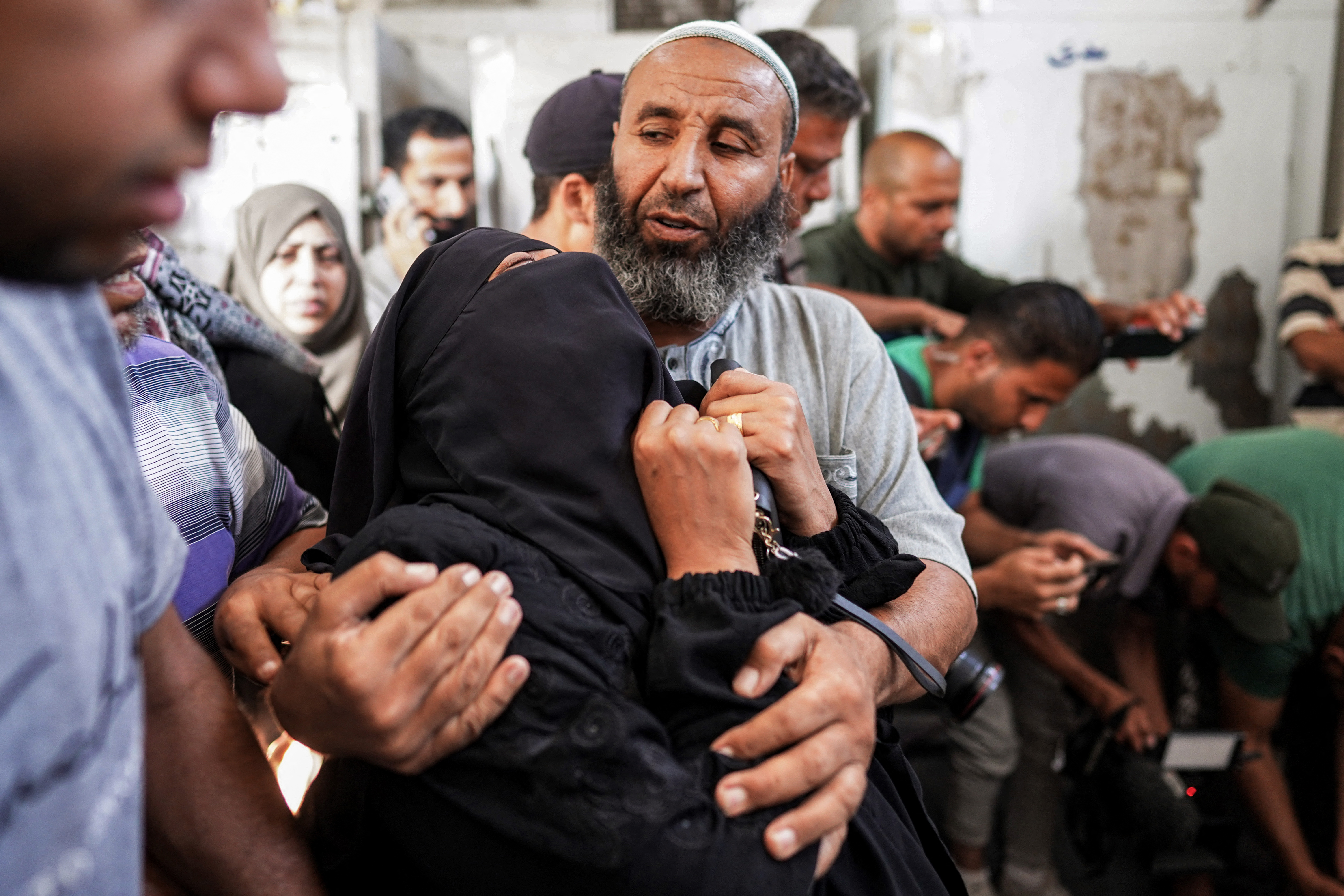 A man comforts a woman mourning her brother who was killed in the aftermath of overnight Israeli bombardment in al-Maghazi in the central Gaza Strip