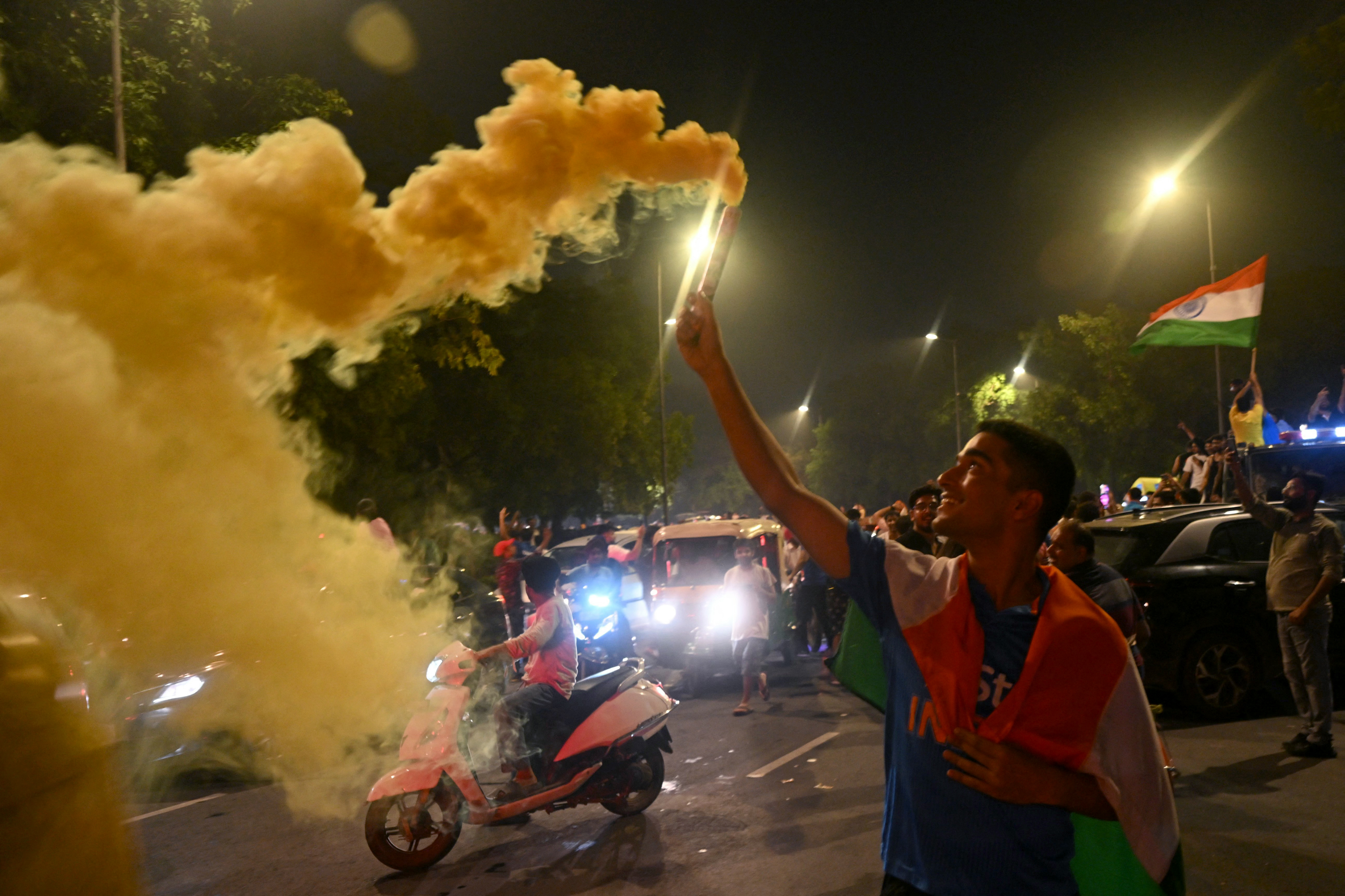 A fan holds a smoke bombs as he celebrates India's victory at the 2024 ICC men's Twenty20 World Cup, at India gate in New Delhi on June 29