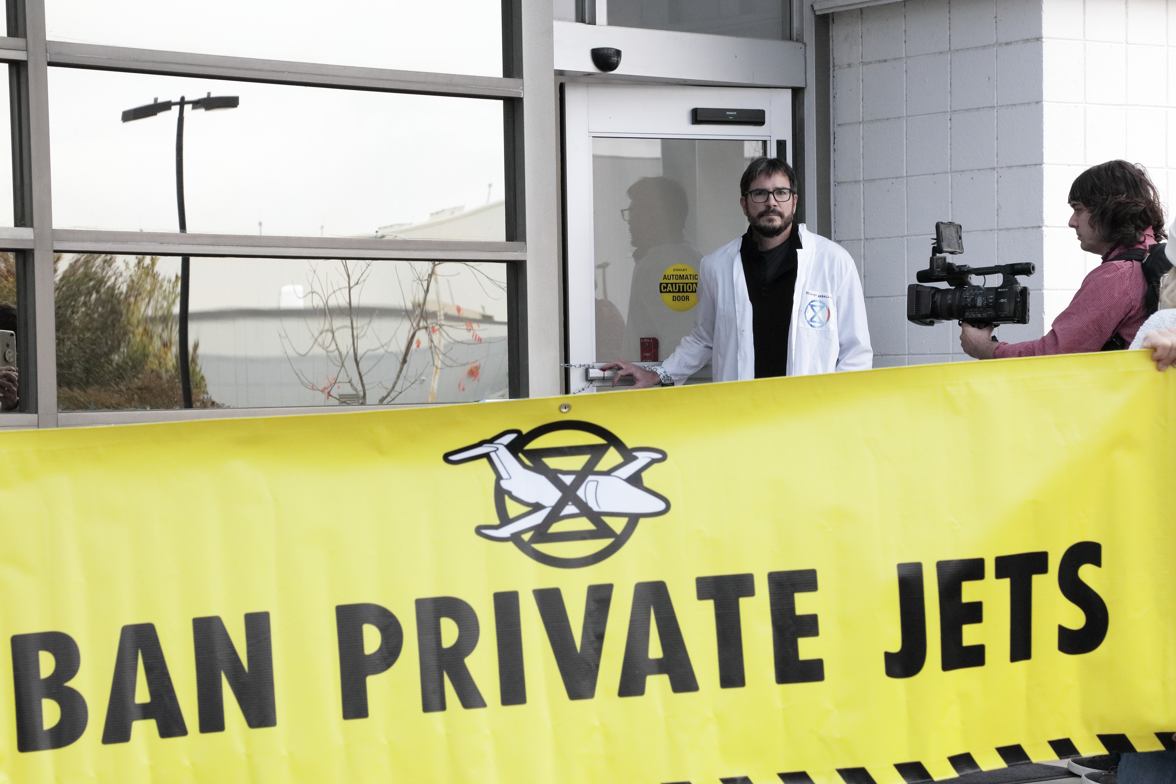 Joining a global day of action to ban private jets, Peter Kalmus and local activists chain shut the doors of a private airport in Charlotte, North Carolina, to underscore the disproportionately high impact the wealthy have in terms of carbon emissions. (2022)