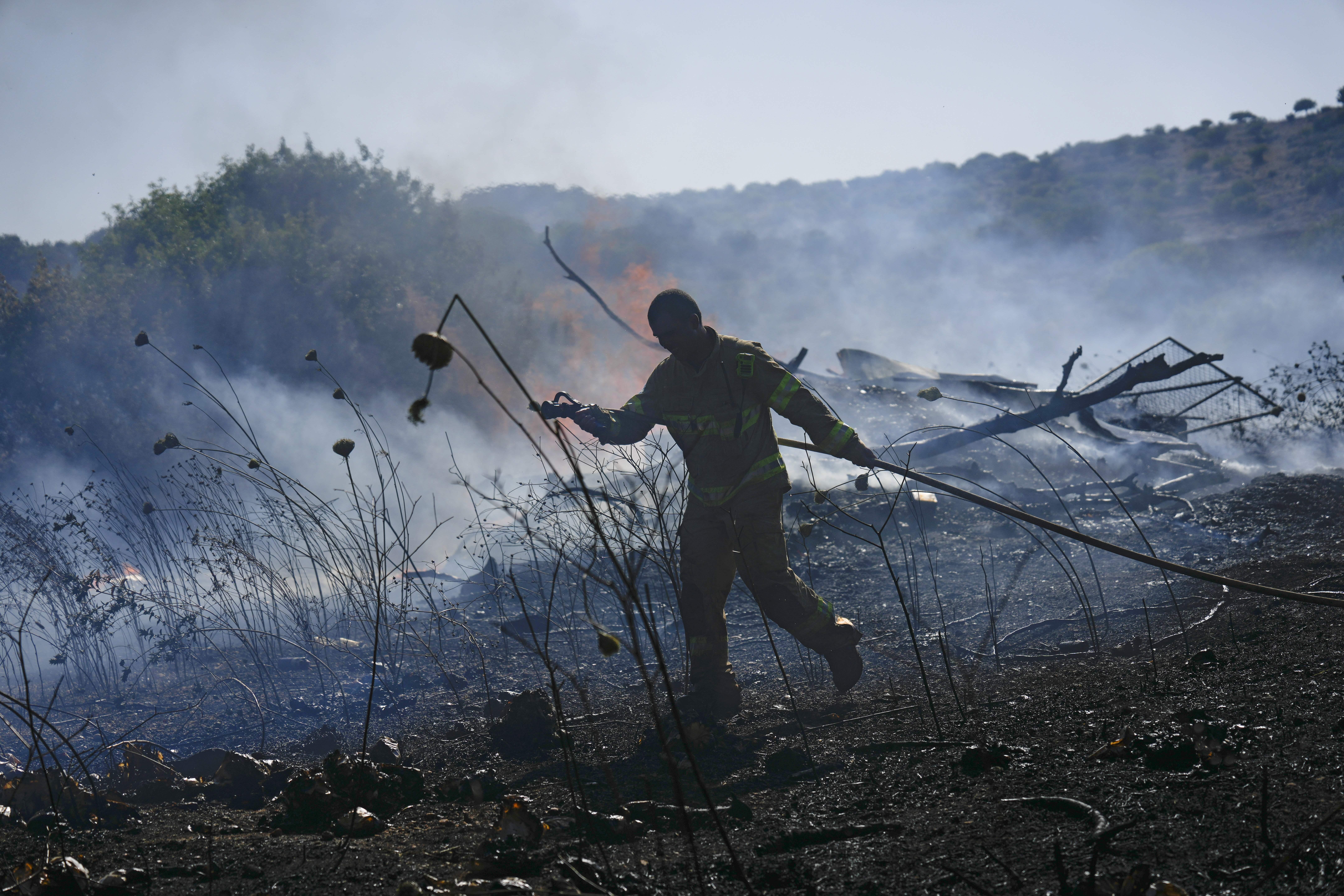 An Israeli firefighter works to extinguish a fire burning in an area near the community of Ramot Naftali, by the border with Lebanon, northern Israel, Tuesday, June 4, 2024