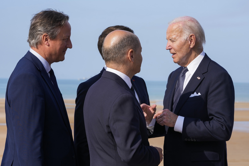 US President Joe Biden, right, talks to German Chancellor Olaf Scholz, second right, French President Emmanuel Macron, back, and British Foreign Secretary David Cameron, left, at the end of an international ceremony to mark the 80th anniversary of D-Day