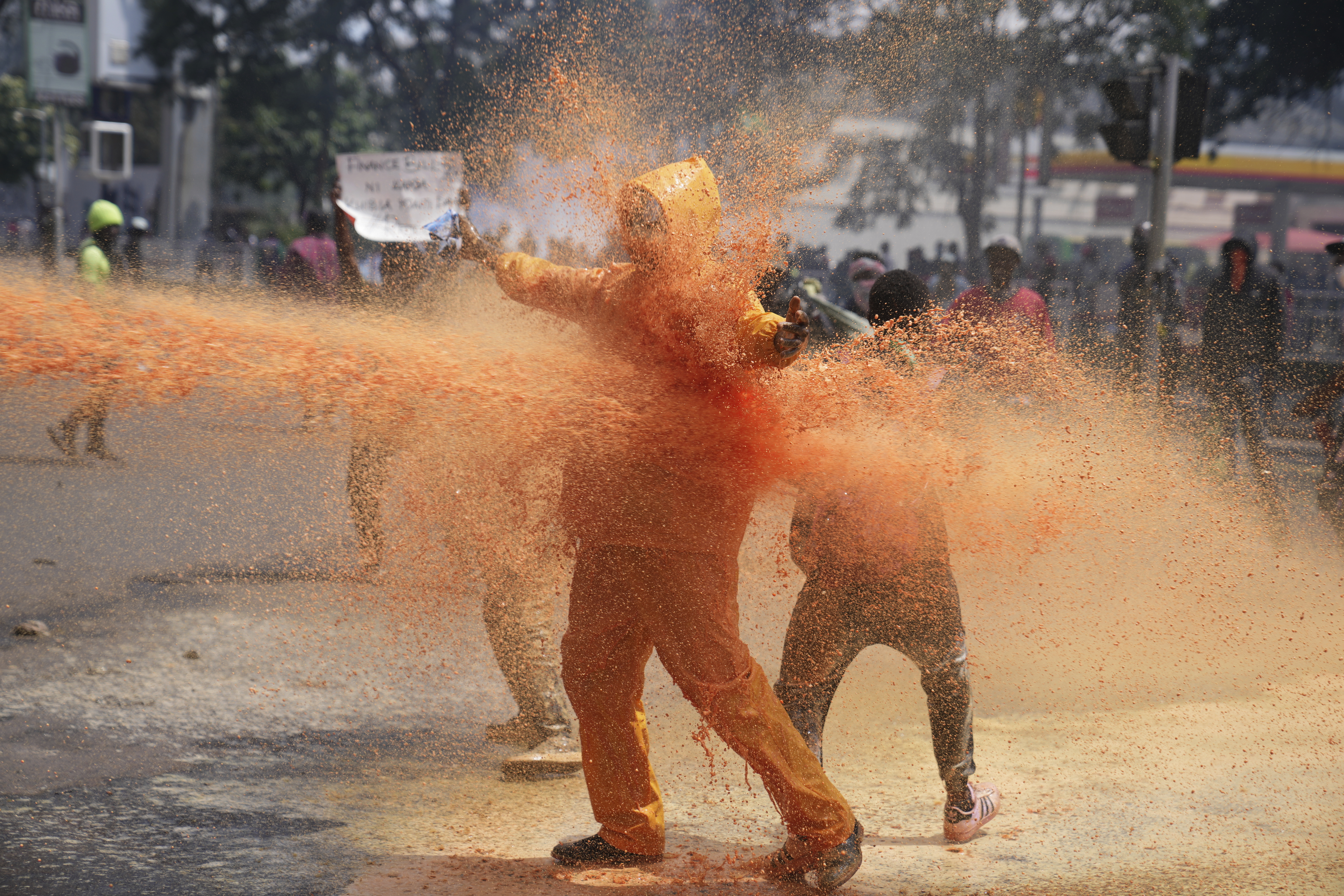 Protesters scatter as Kenya police spray a water canon at them during a protest over proposed tax hikes in a finance bill in downtown Nairobi, Kenya