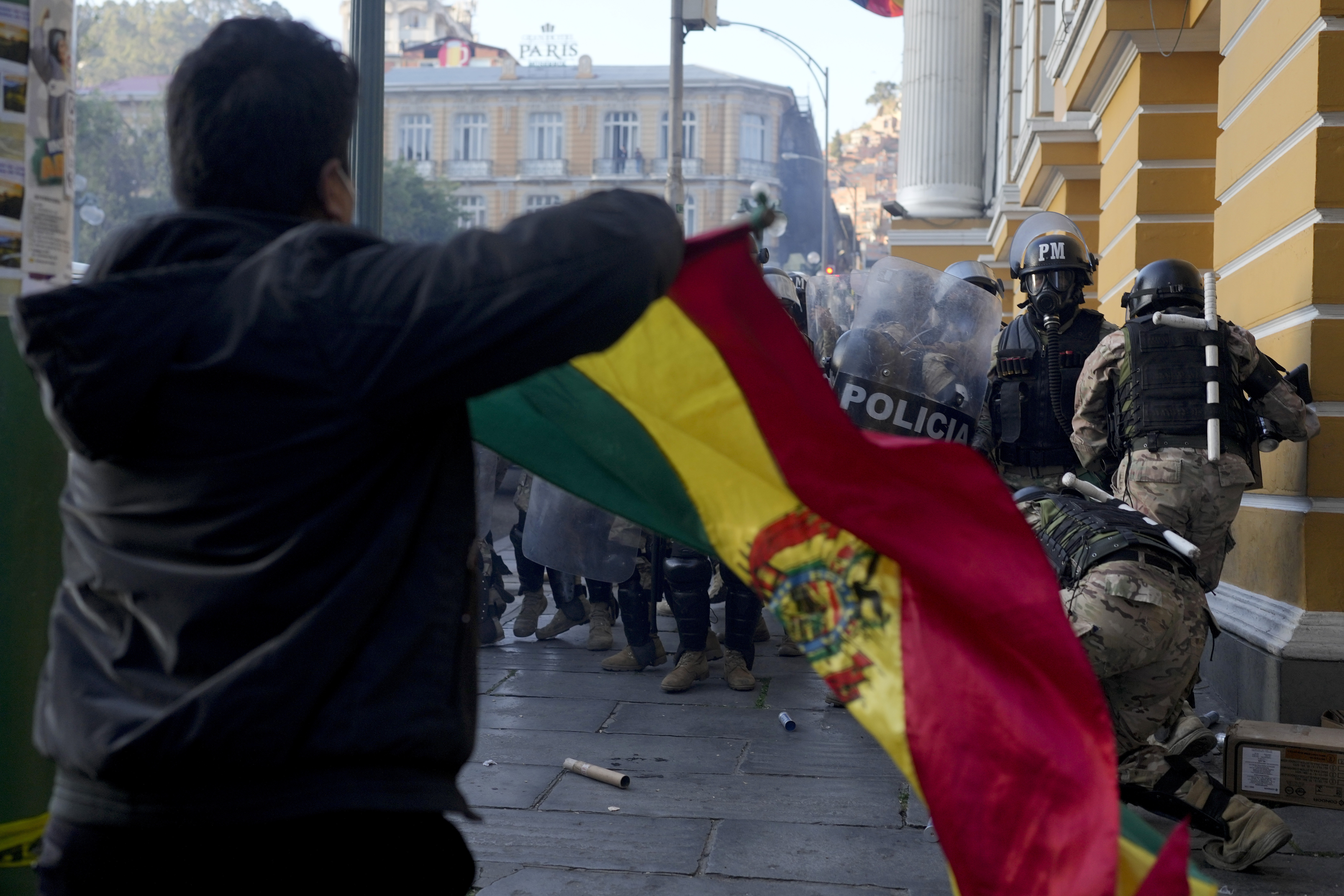 A supporter of President Luis Arce waves a Bolivian flag as soldiers flee from Plaza Murillo, after a failed coup attempt, in La Paz, Bolivia, Wednesday, June 26