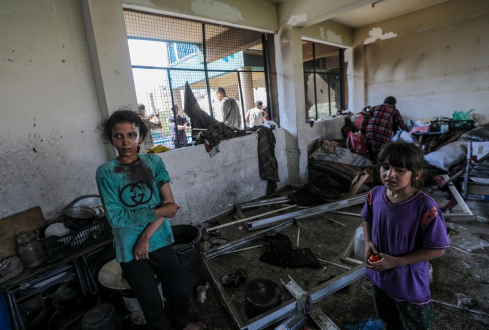 epa11478359 An injured Palestinian girl (L) stands among debris in a damaged UNRWA school following an Israeli air strike in Al Nuseirat refugee camp, central Gaza Strip, 14 July 2024. At least 12 people were killed following an Israeli air strike in the camp, according to the Palestinian Ministry of Health. The Israeli military stated on 14 July, that the Israeli Air Force (IAF) struck the area of UNRWA's Abu Oraiban School School building in Nuseirat, claiming that the location served as a 'hideout and operational infrastructure' to direct and carry attacks against Israeli troops operating in the Gaza Strip. More than 38,000 Palestinians and over 1,400 Israelis have been killed, according to the Palestinian Health Ministry and the Israel Defense Forces (IDF), since Hamas militants launched an attack against Israel from the Gaza Strip on 07 October 2023, and the Israeli operations in Gaza and the West Bank which followed it. EPA-EFE/MOHAMMED SABER