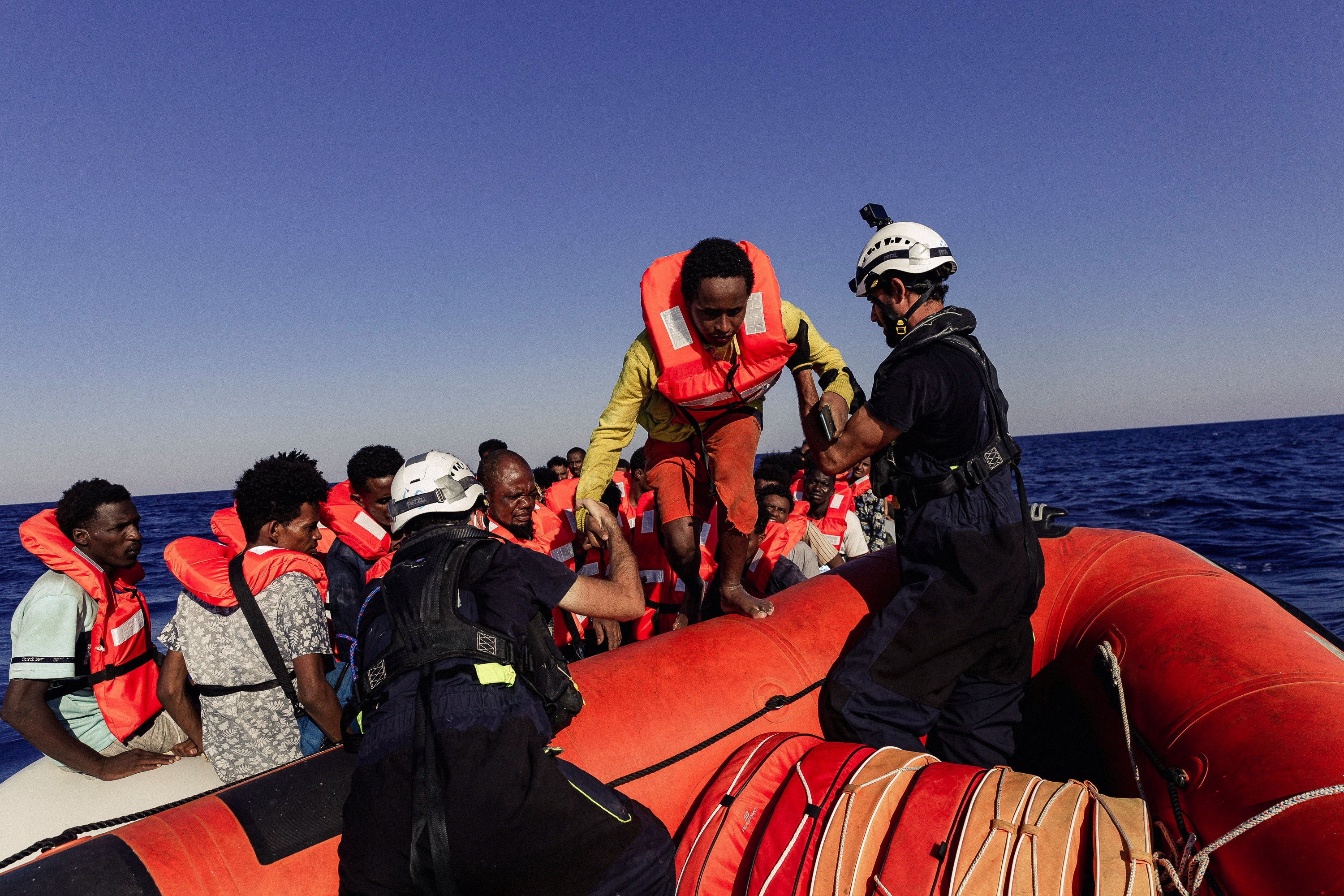 Sea-Watch crew member helps a migrant boarding a dinghy in the Mediterranean Sea, July 23, 2022. Nora Bording/Sea-Watch/Handout via REUTERS ATTENTION EDITORS - THIS IMAGE HAS BEEN SUPPLIED BY A THIRD PARTY. MANDATORY CREDIT