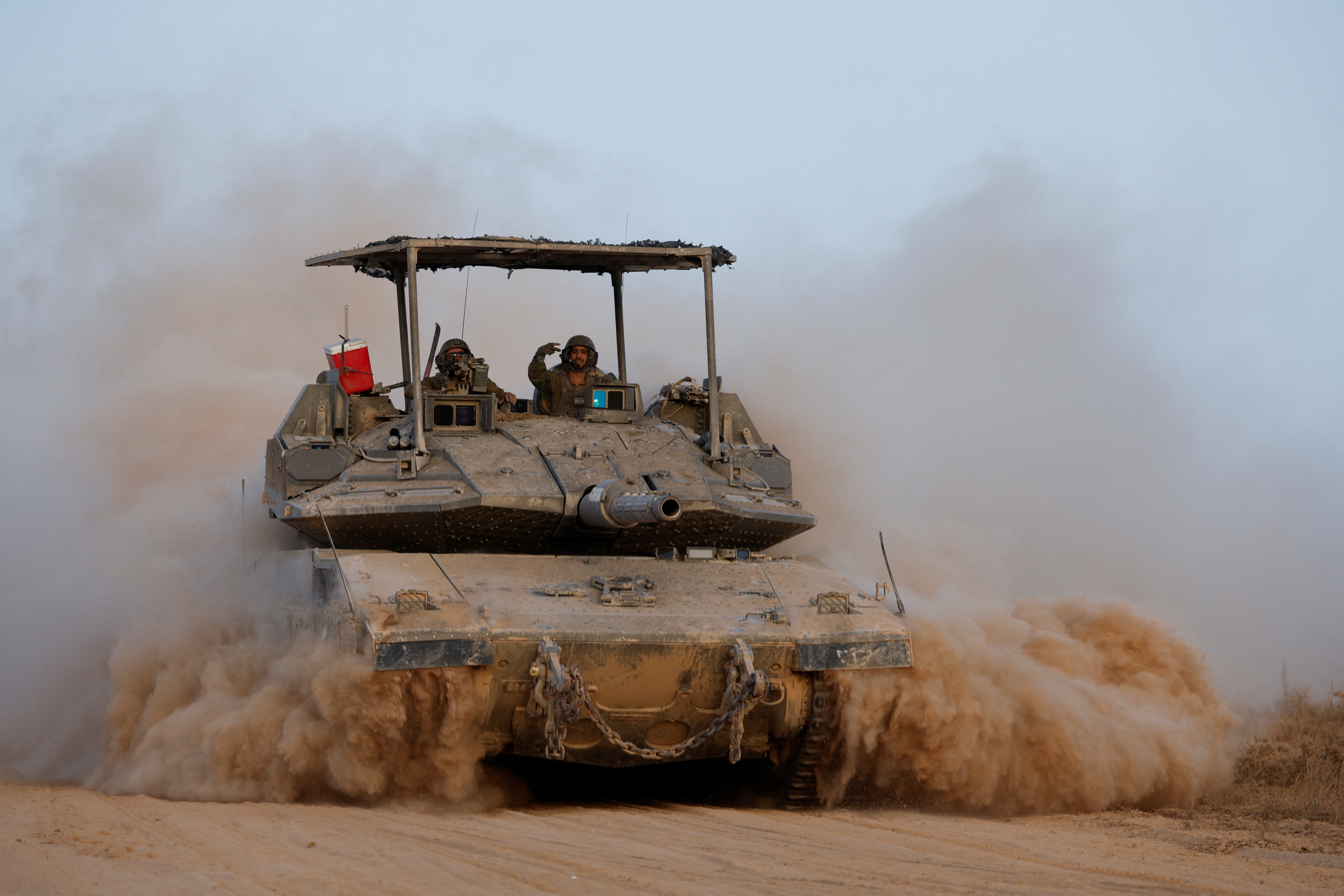 An Israeli soldier gestures atop a tank near the separation fence before it enters Gaza
