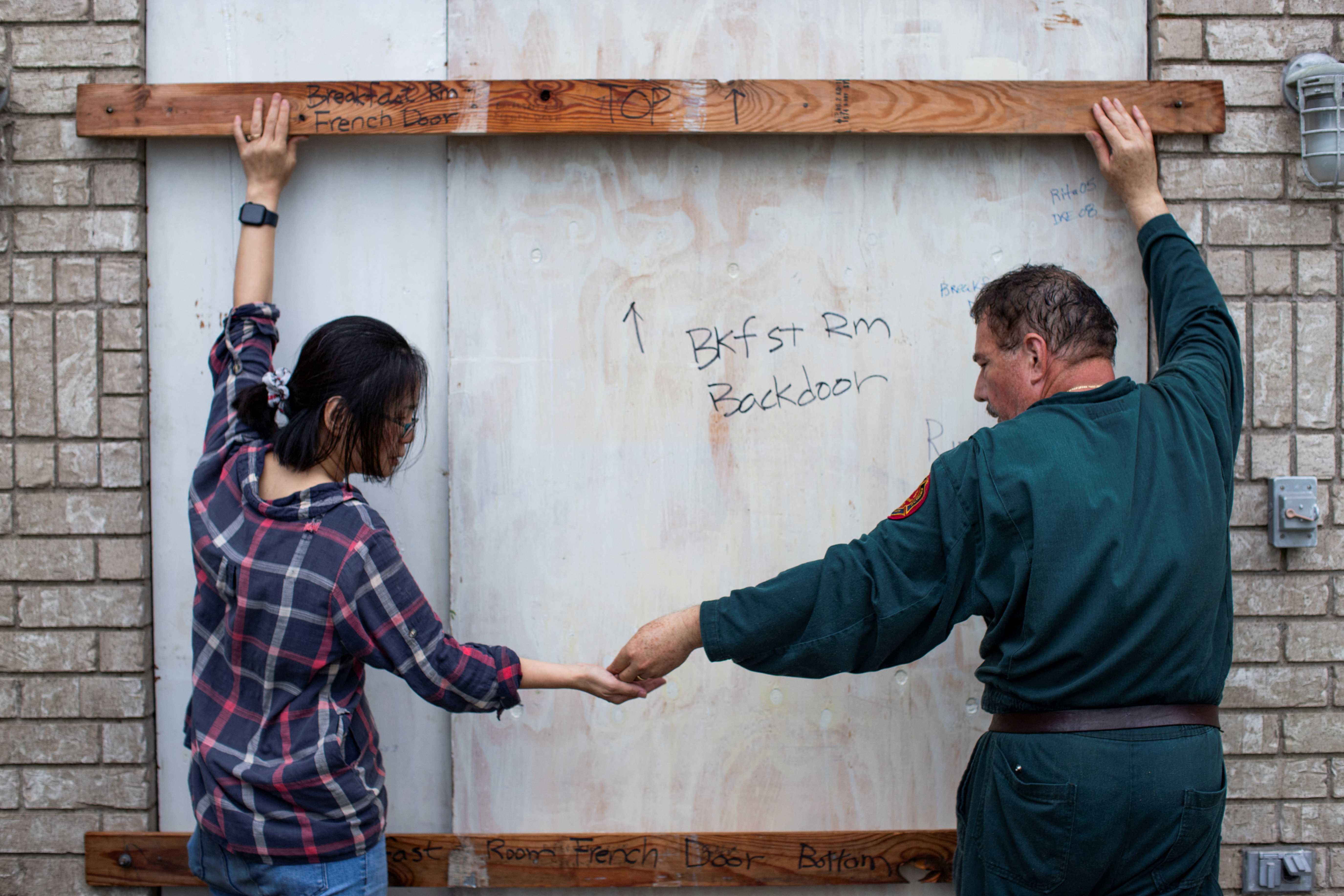 Shan Mei Martinez and Mario Martinez attach door braces to secure their back bay-facing door, as residents prepare for the arrival of Hurricane Beryl in Port Lavaca, Texas, U.S. July 7, 2024. REUTERS/Kaylee Greenlee Beal