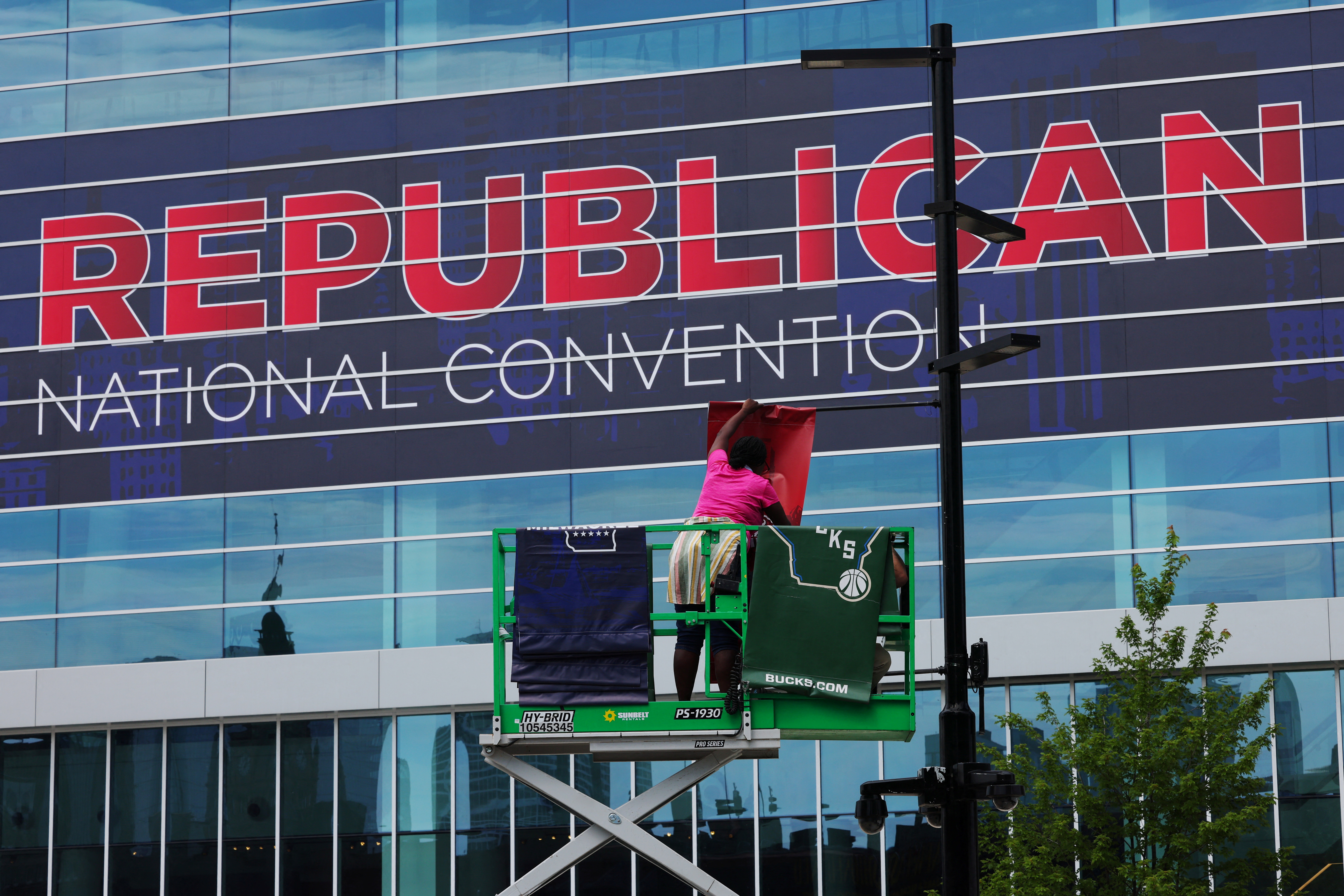 A worker on a crane puts up a sign on a street light outside the Republican National Convention. 
