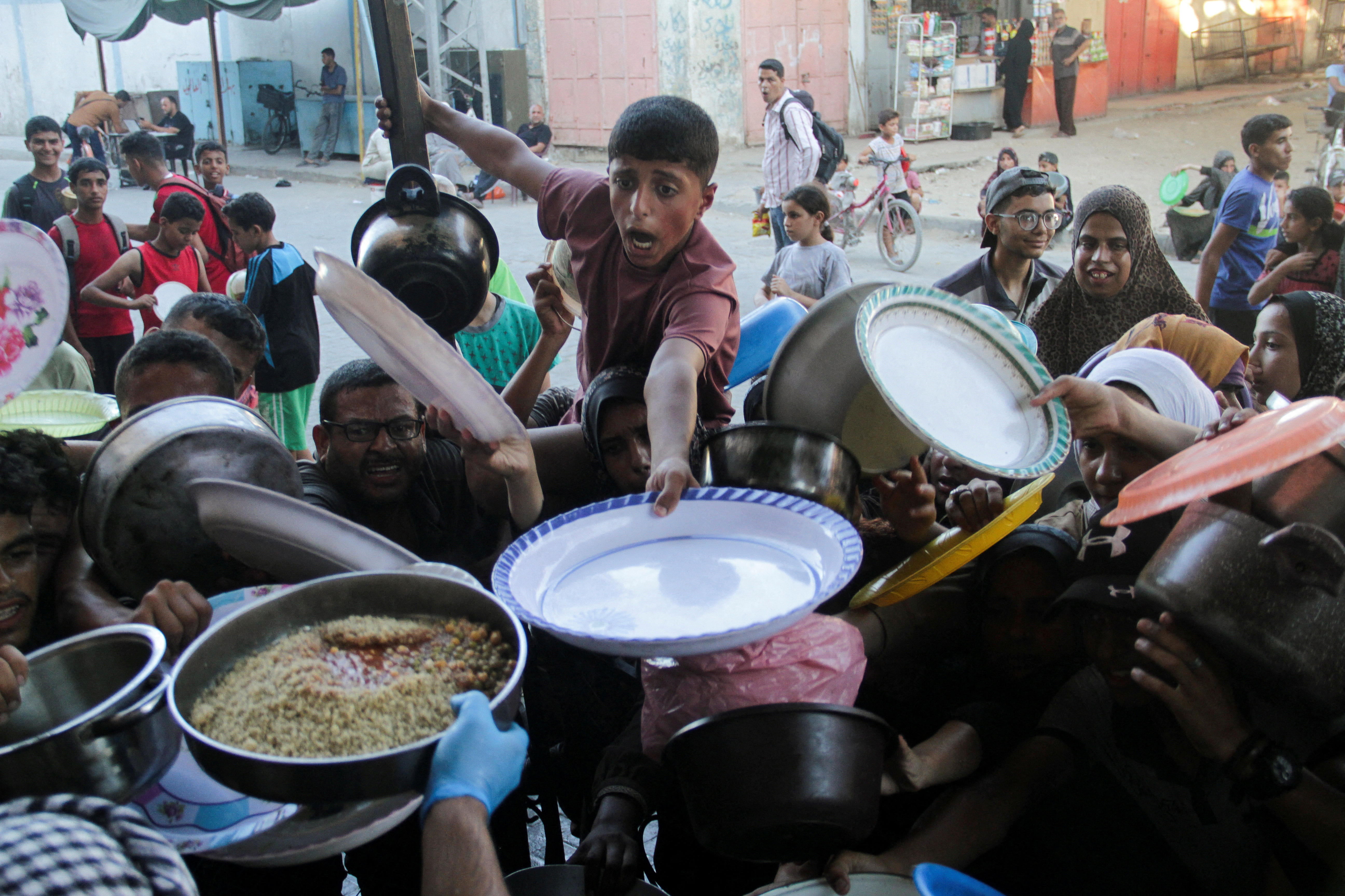 Palestinian children gather to receive food cooked by a charity kitchen, amid food scarcity, as Israel-Hamas conflict continues, in the northern Gaza Strip, July 18, 2024. REUTERS/Mahmoud Issa