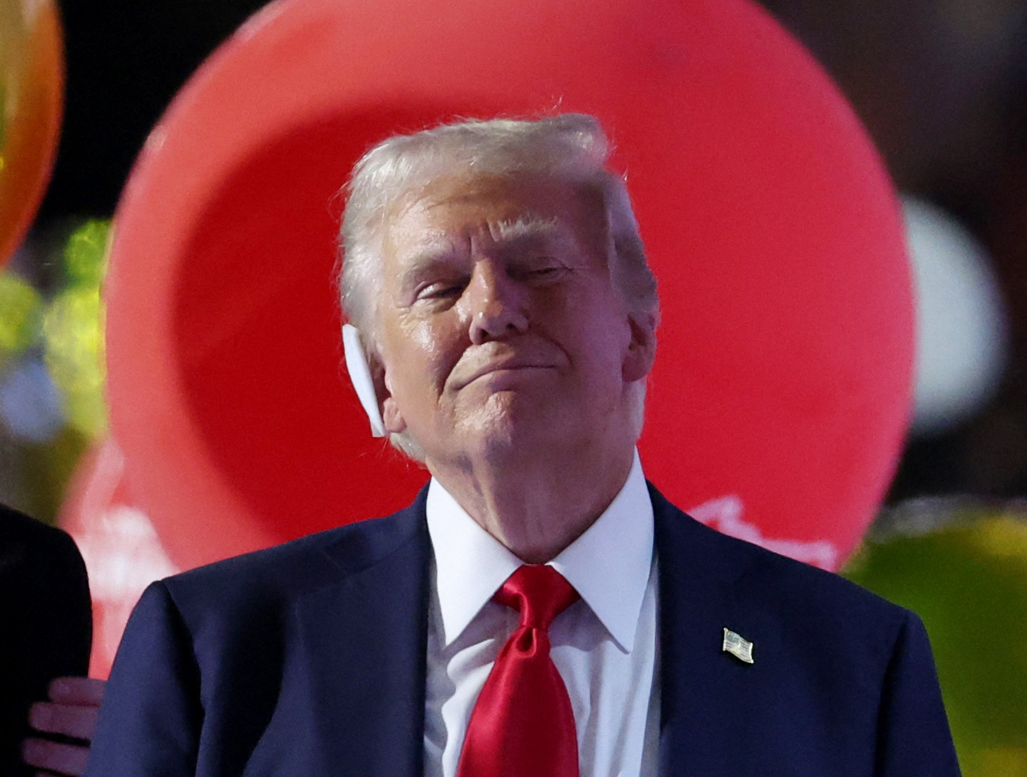 Trump smiles as a red balloon floats behind him.