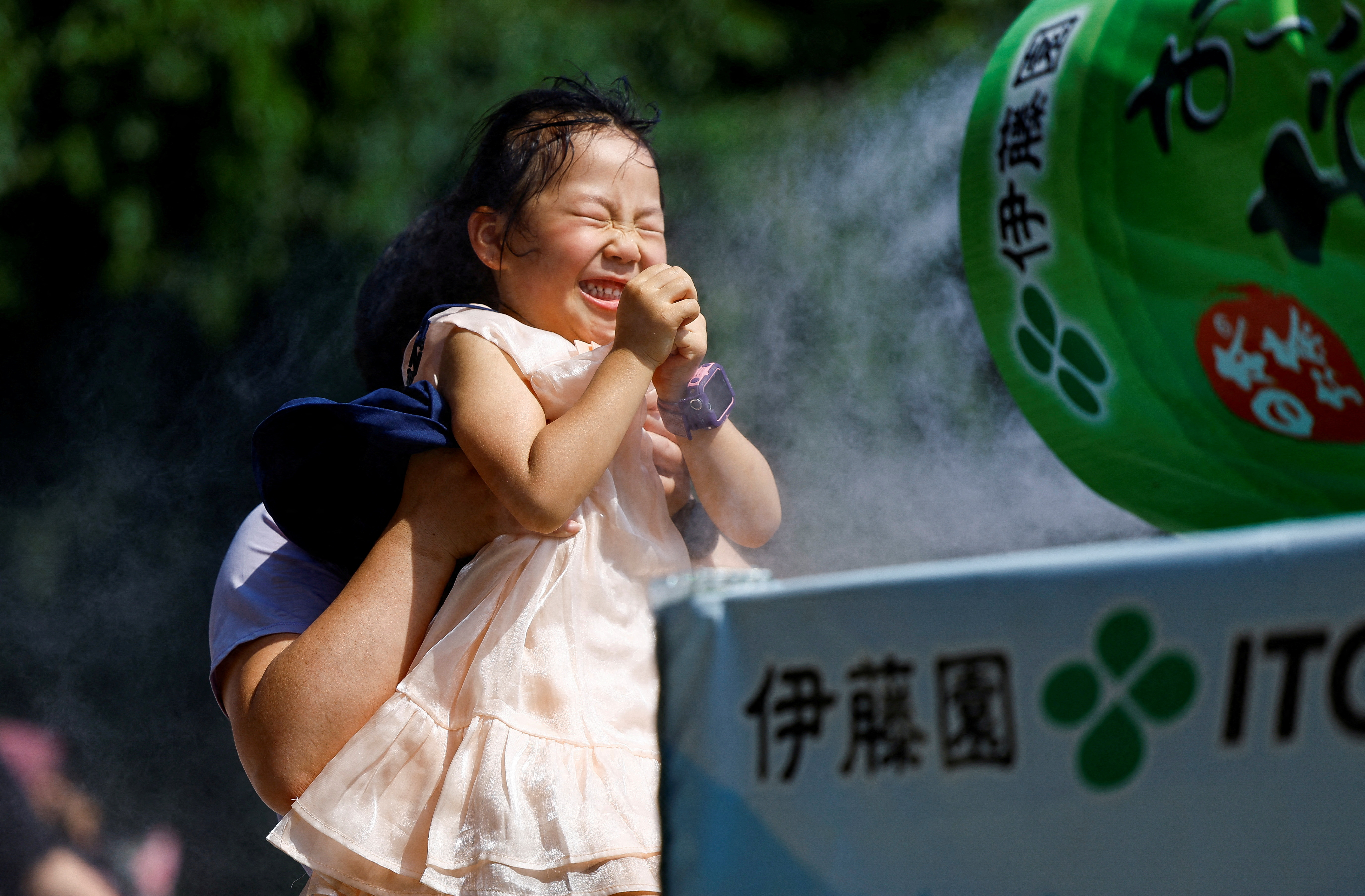 A child reacts as a family takes a break next to a cooling mist at the Sensoji temple