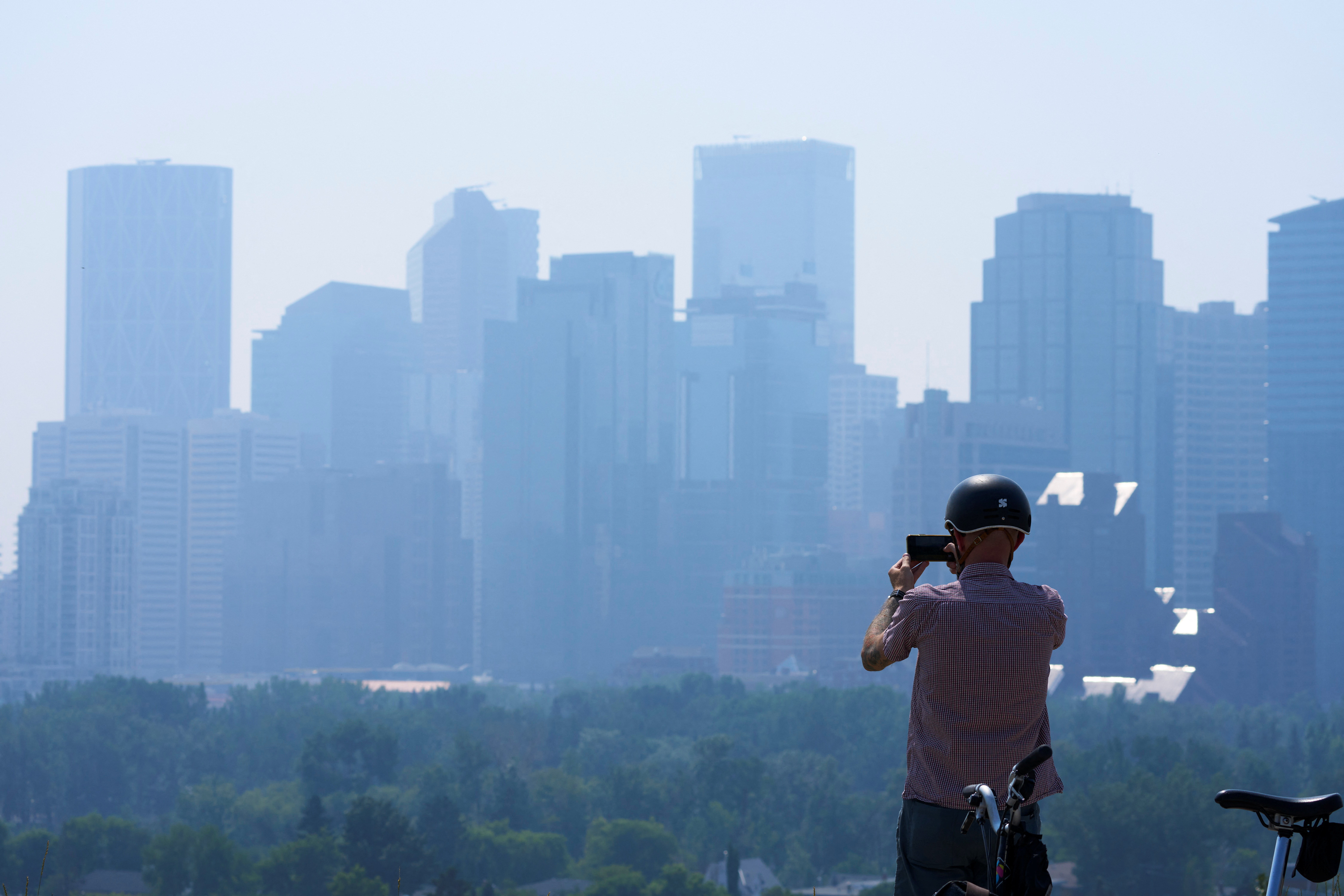 A person takes a photo of wildfire smoke in Calgary, Alberta, Canada