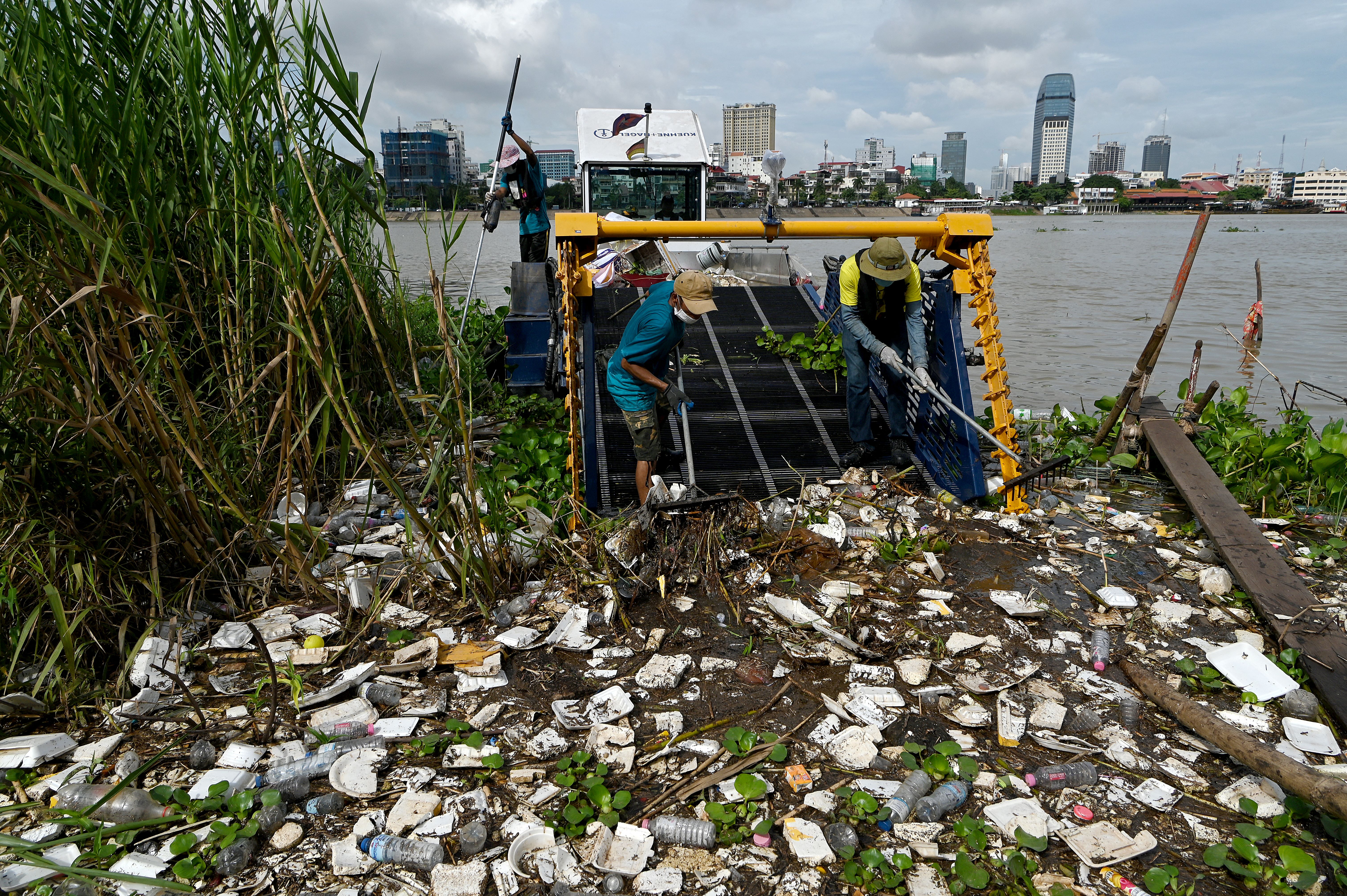 Volunteers gather rubbish into a boat on the Tonle Sap river during World Cleanup Day in Phnom Penh on September 17, 2022. (Photo by TANG CHHIN Sothy / AFP)