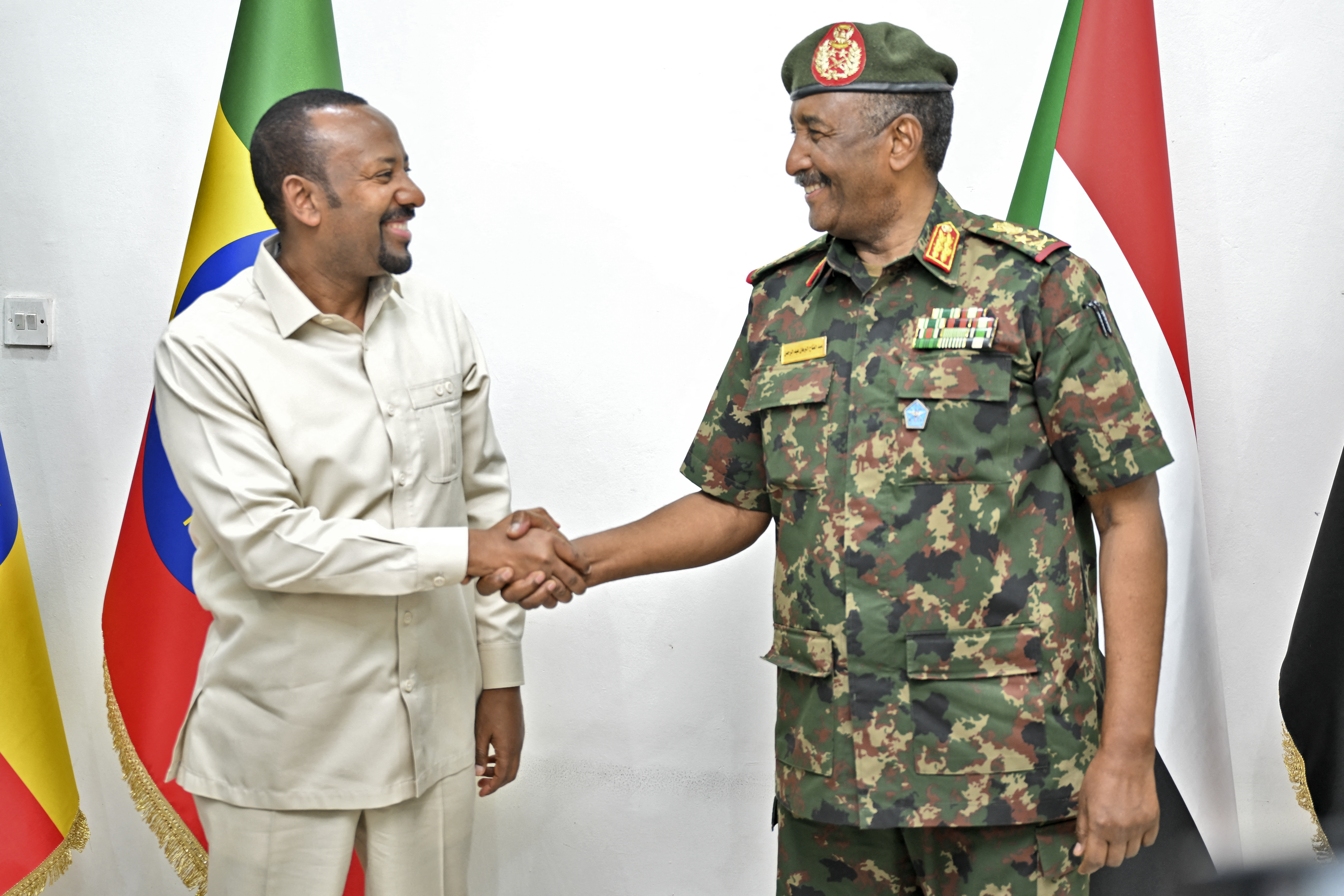 The President of Sudan's Transitional Sovereignty Council (TSC) General Abdel Fattah al-Burhan (R) welcomes Ethiopia's Prime Minister Abiy Ahmed