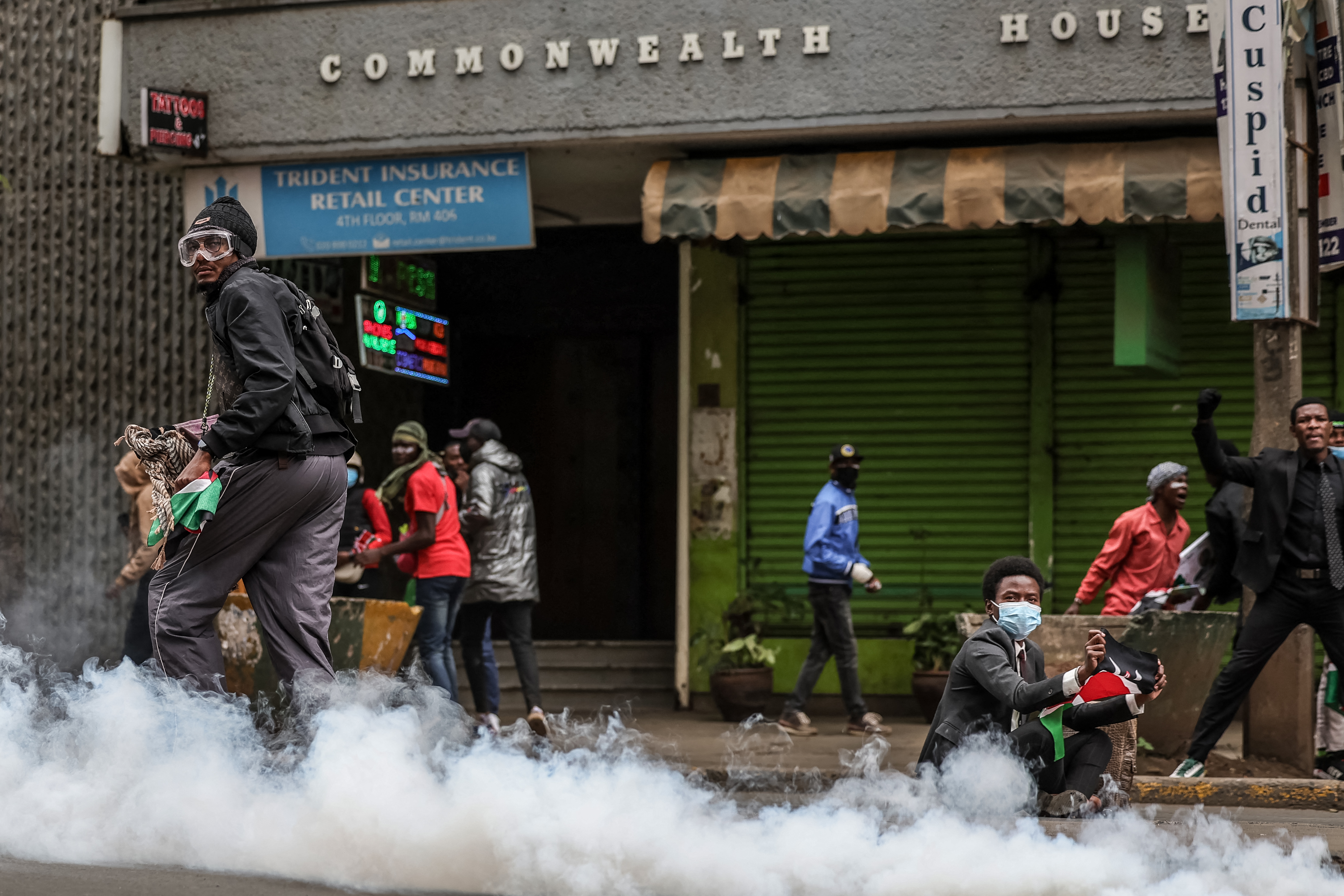 A protester (R) waves a Kenyan flag as a cloud of tear gas is released from a canister during renewed demonstrations in Nairobi on July 16, 2024. - Police were out in force in the centre of Kenya's capital on Tuesday after calls for more demonstrations against the embattled government of President William Ruto. Activists led by young Gen-Z Kenyans launched peaceful rallies a month ago against deeply unpopular tax hikes but they descended into deadly violence last month, prompting Ruto to drop the planned increases. (Photo by Tony Karumba / AFP)