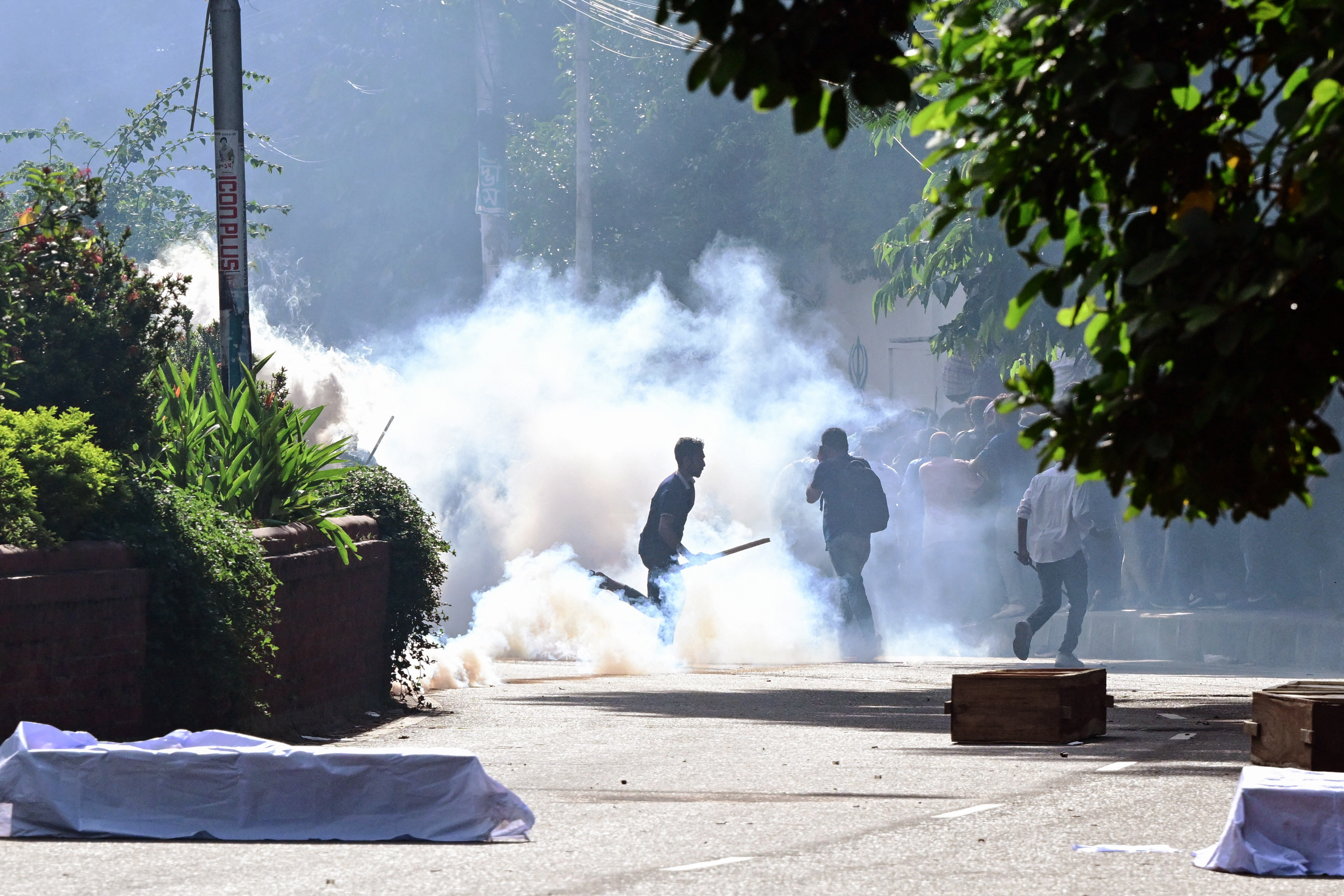 Bangladesh police personnel fire tear shells as students protest against quotas in government jobs alongside symbolic coffins of victims who died in a clash with the police