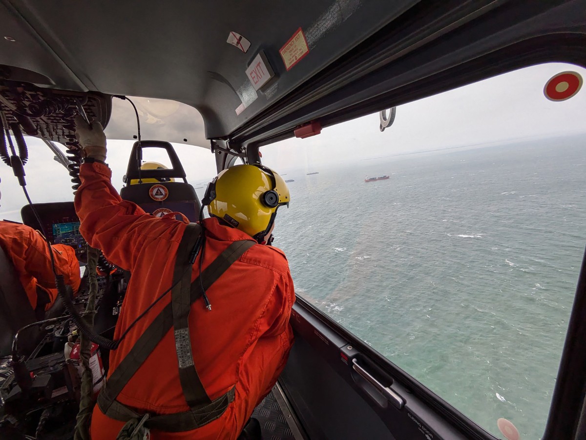 Coast Guard personnel aboard a helicopter conducting an aerial survey off Manila, after oil tanker MT Terra Nova capsized