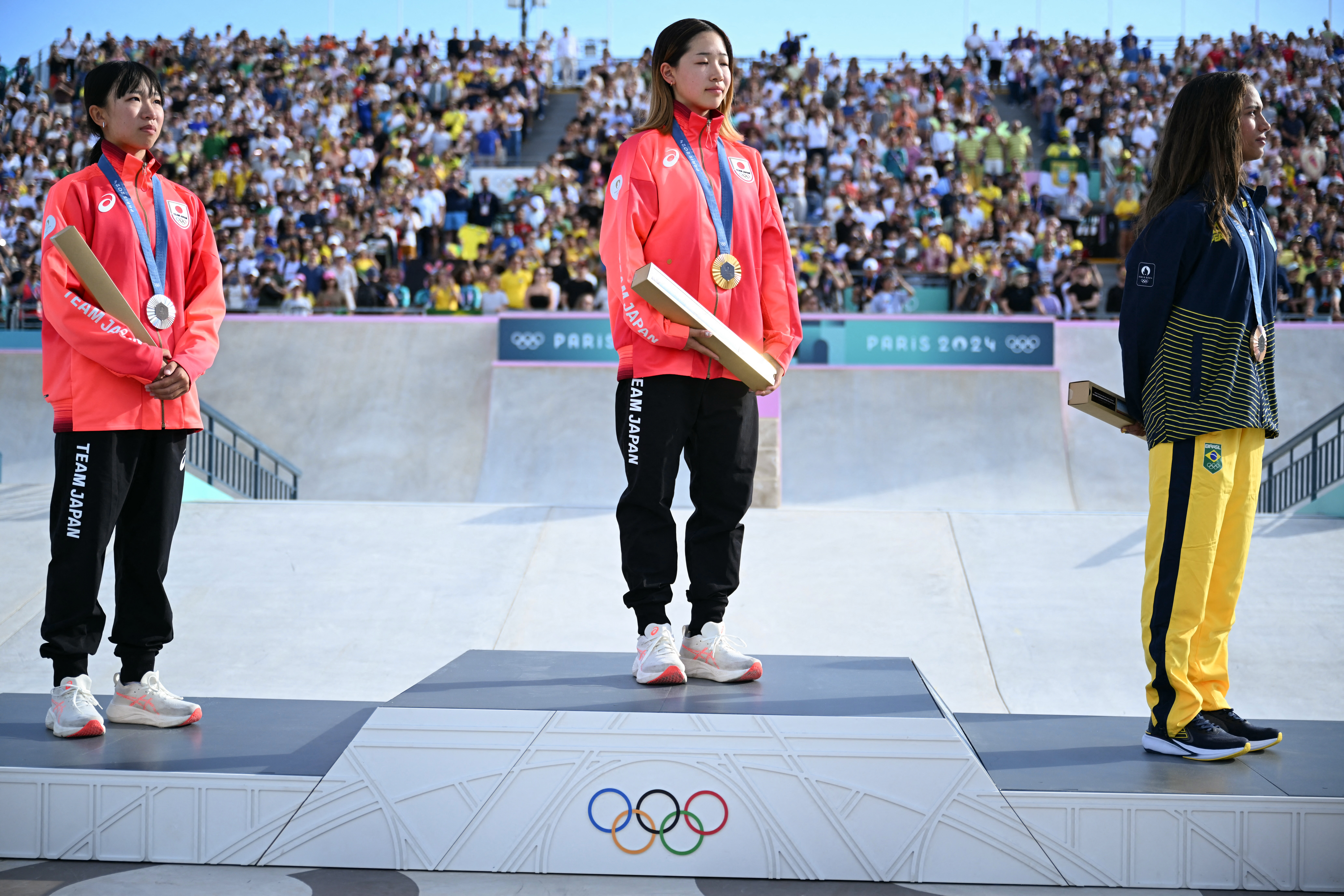 Three skateboaders on Olympic dias.