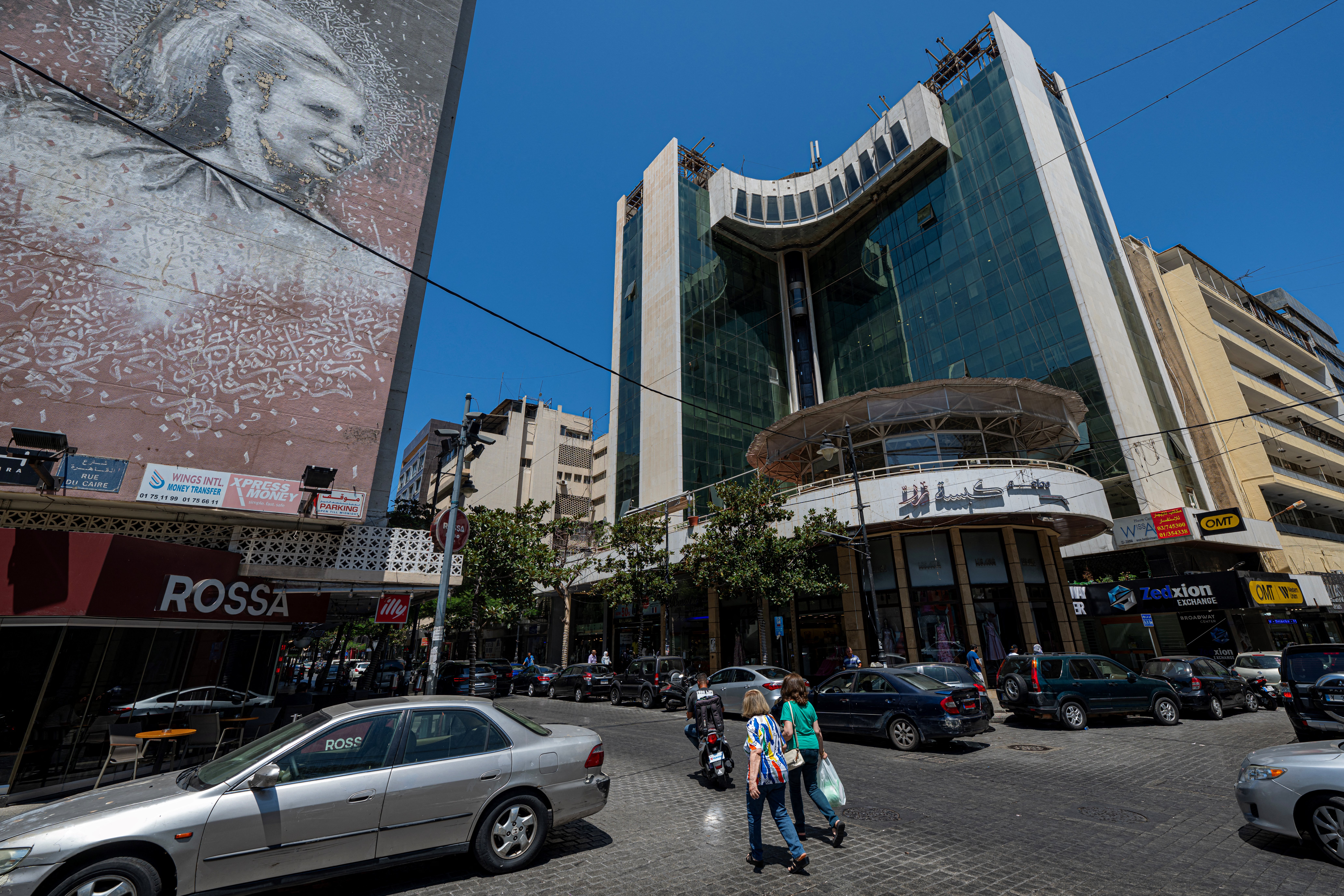 People walk past a mural bearing a portrait of Lebanon's late iconic singer Sabah in the heart of Beirut's Hamra shopping district