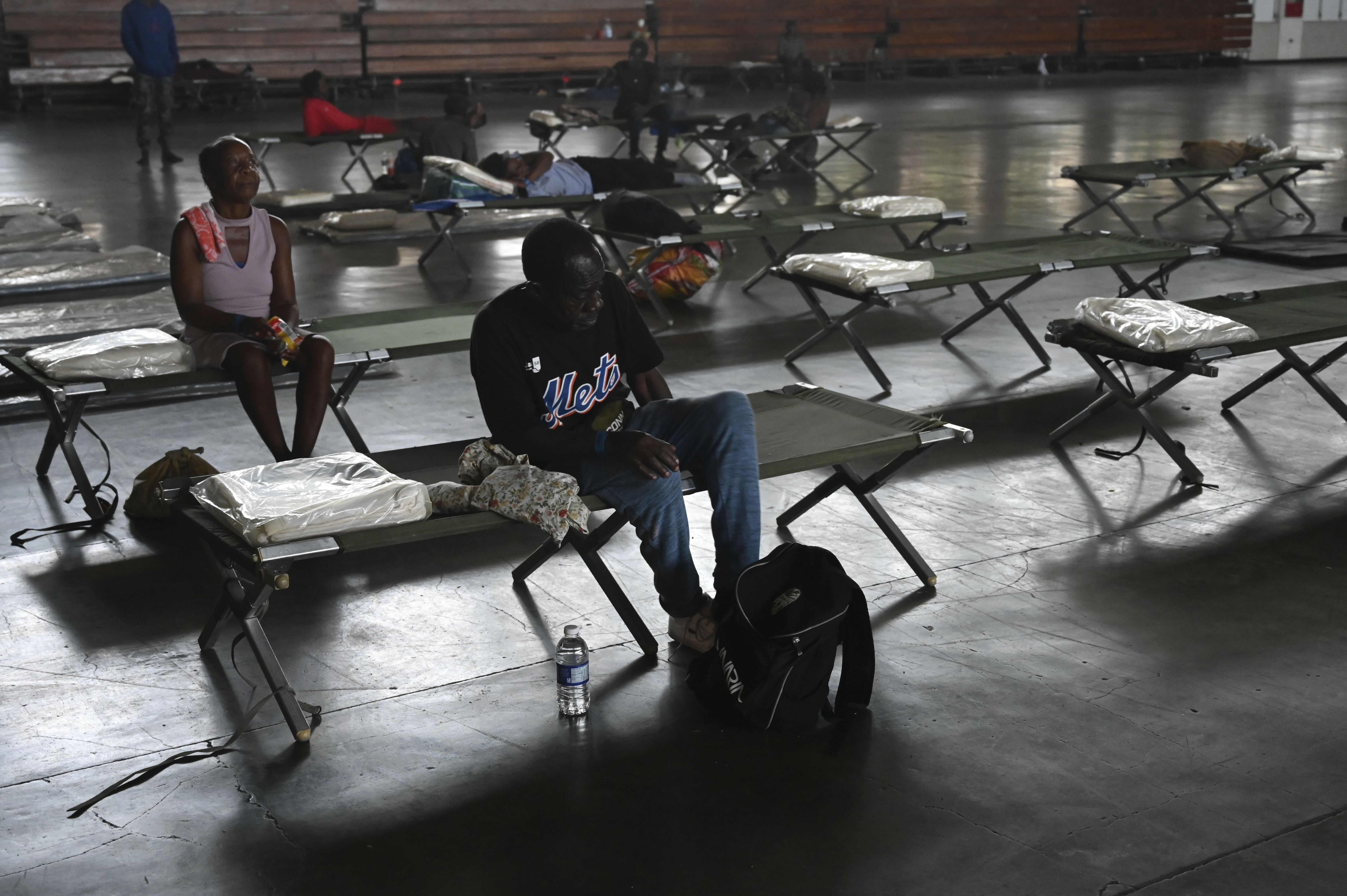 People sit on cots in the National Arena that has been transformed into a shelter in the aftermath of Hurricane Beryl, in Kingston, Jamaica