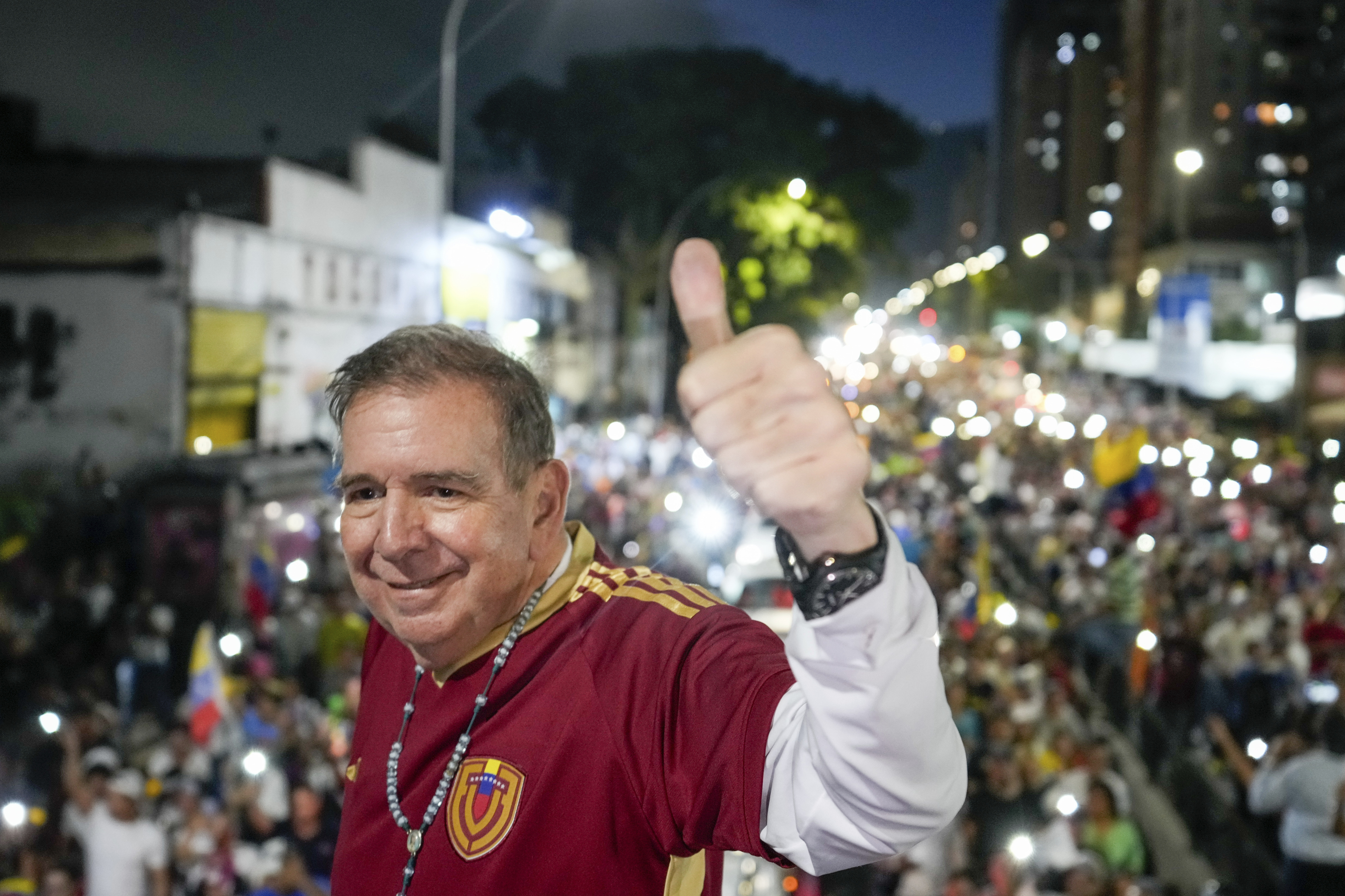Edmundo Gonzalez flashes a thumbs-up as he stands above crowds gathered for a rally.