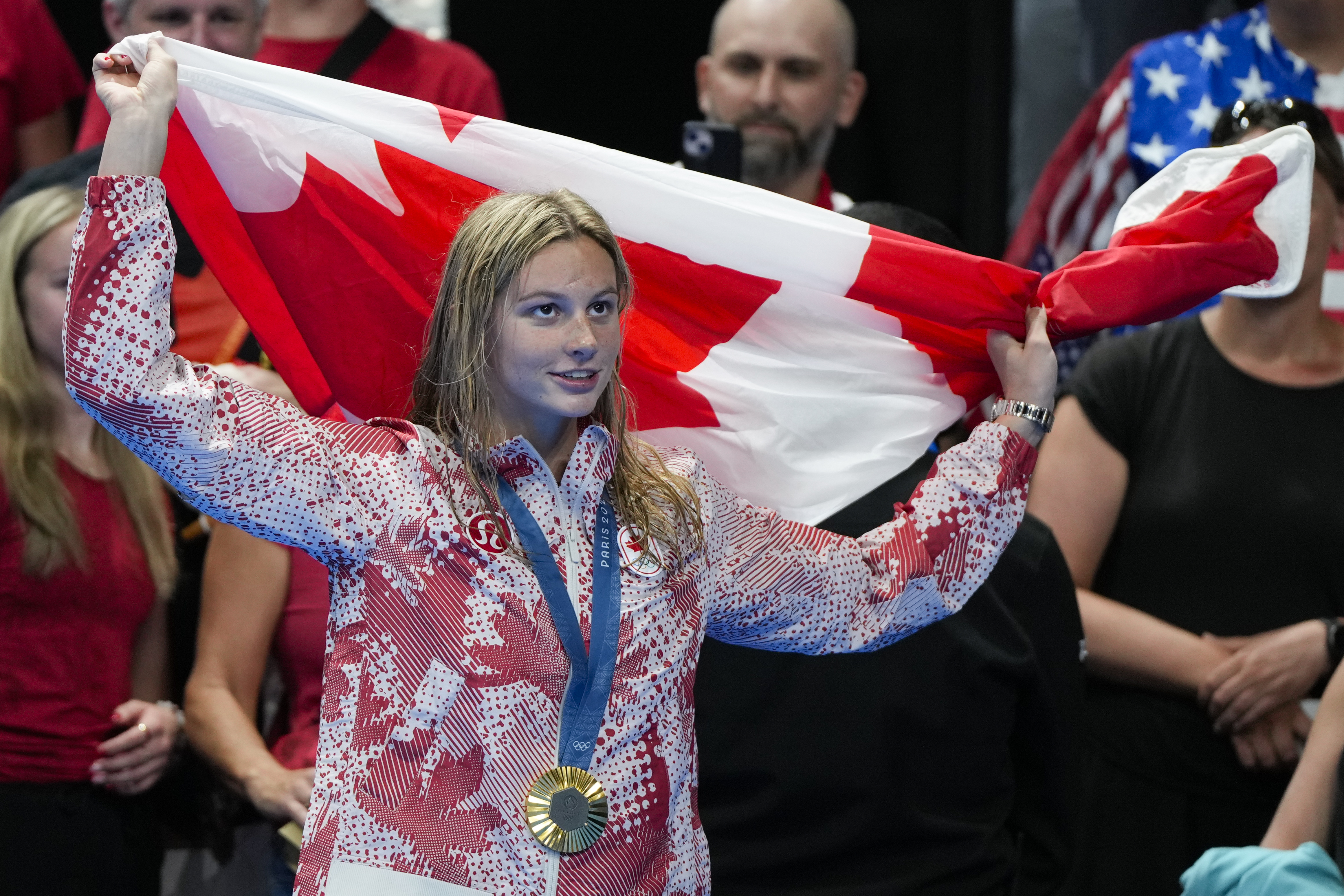 Summer McIntosh, of Canada, holds her national flag after winning the women's 400-meter individual medley final at the 2024 Summer Olympics, Monday, July 29, 2024, in Nanterre, France. (AP Photo/Matthias Schrader)