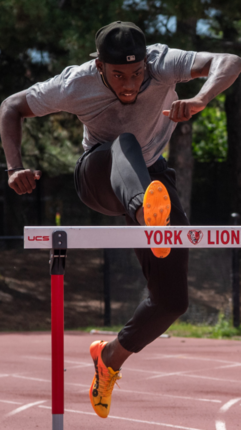Tamarri Lindo leaps over a hurdle on an outdoor track.