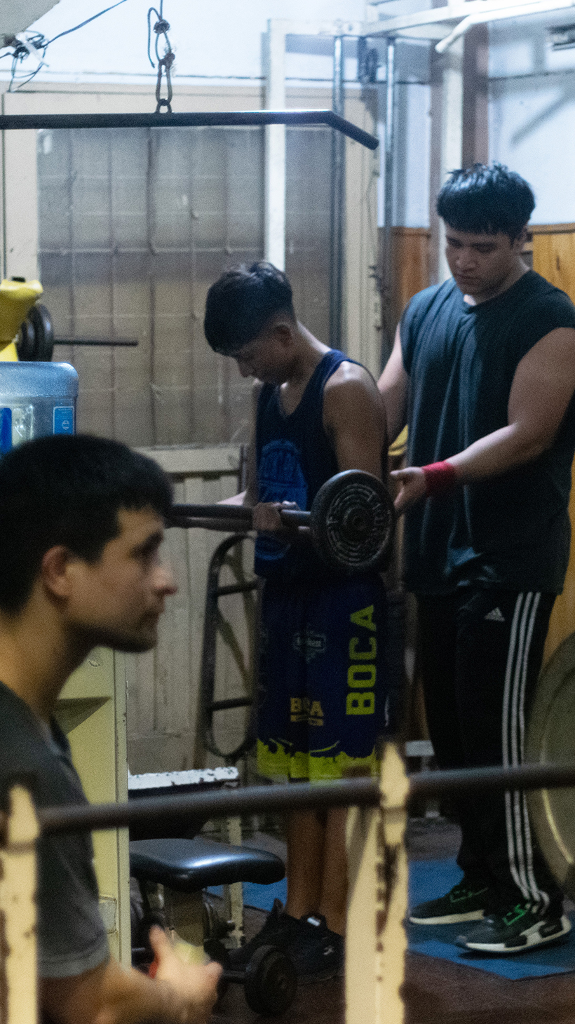 Young people use a work-out room in Argentina to lift weights.