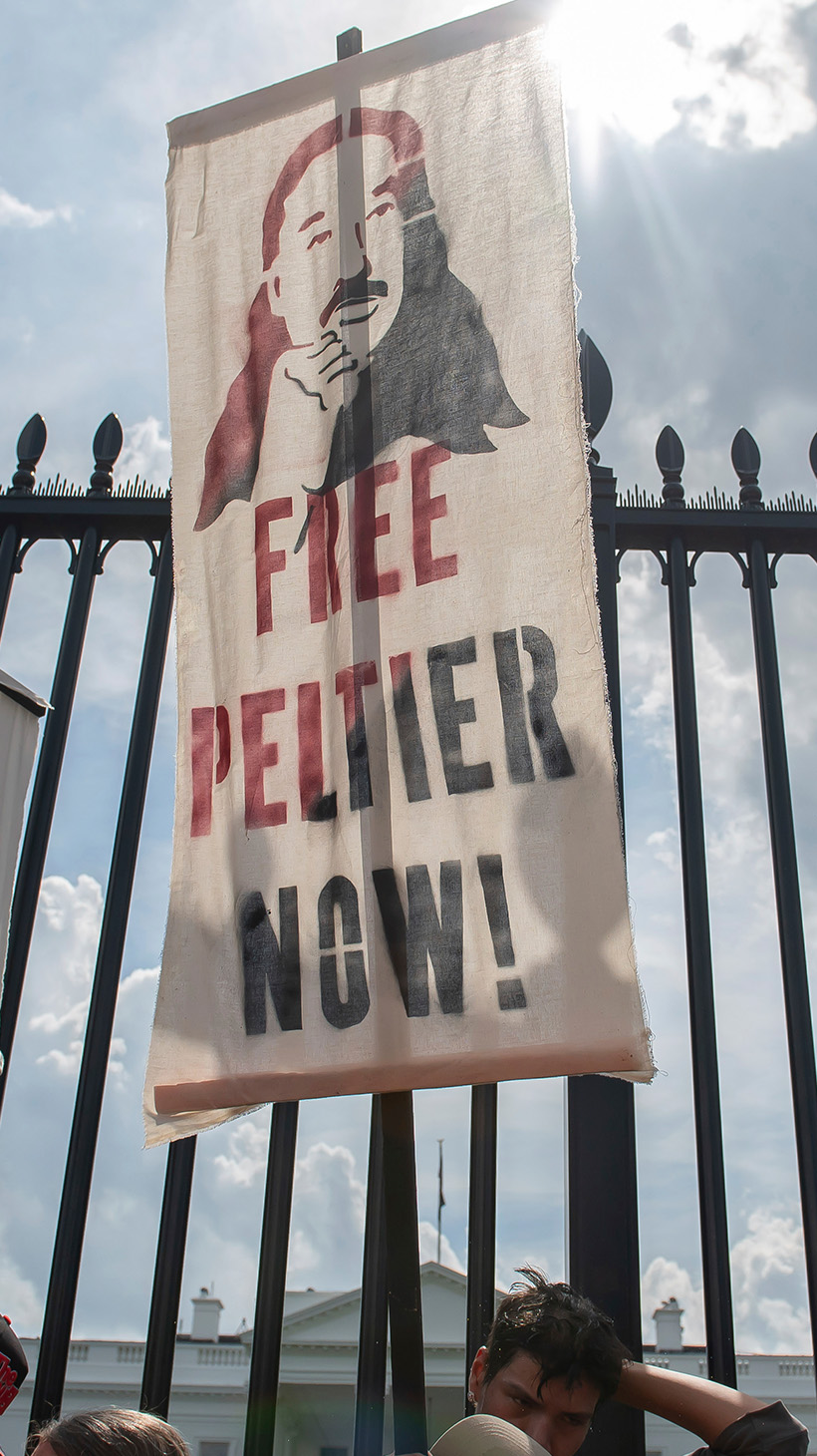 An advocate lifts a picket sign that reads "Free Peltier now."