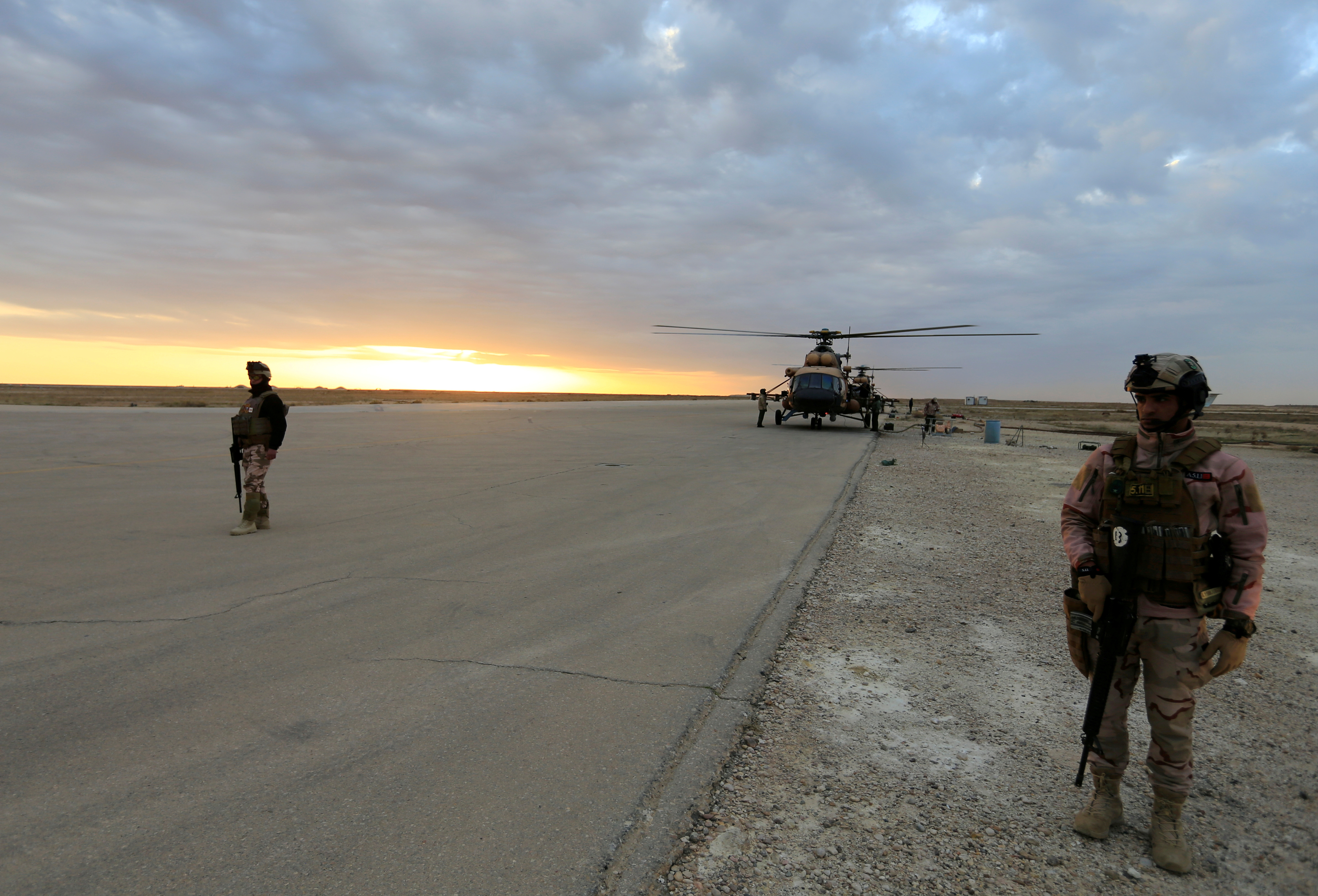 Iraqi security forces are seen at Ain al-Asad airbase near a military helicopter in Anbar province