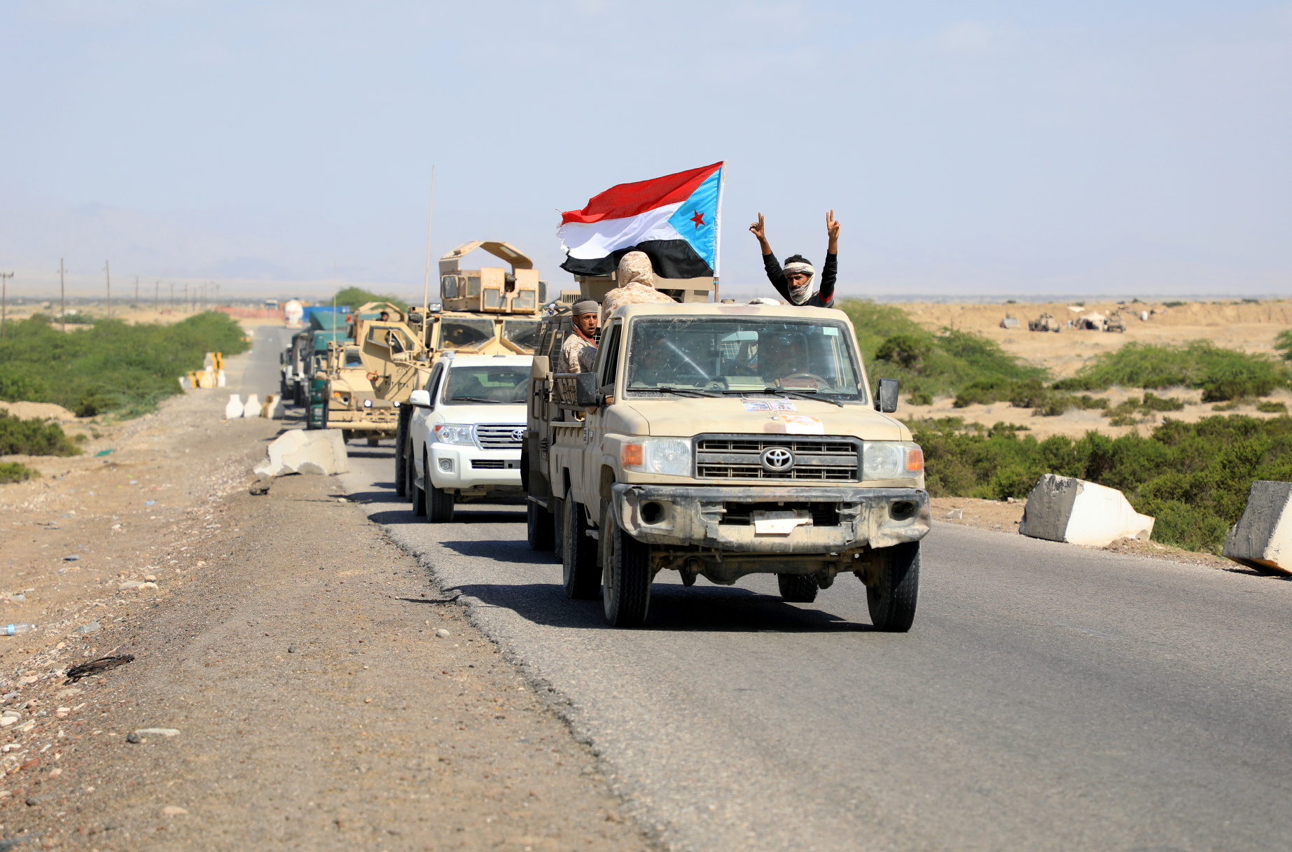 Fighters waving out of military vehicles