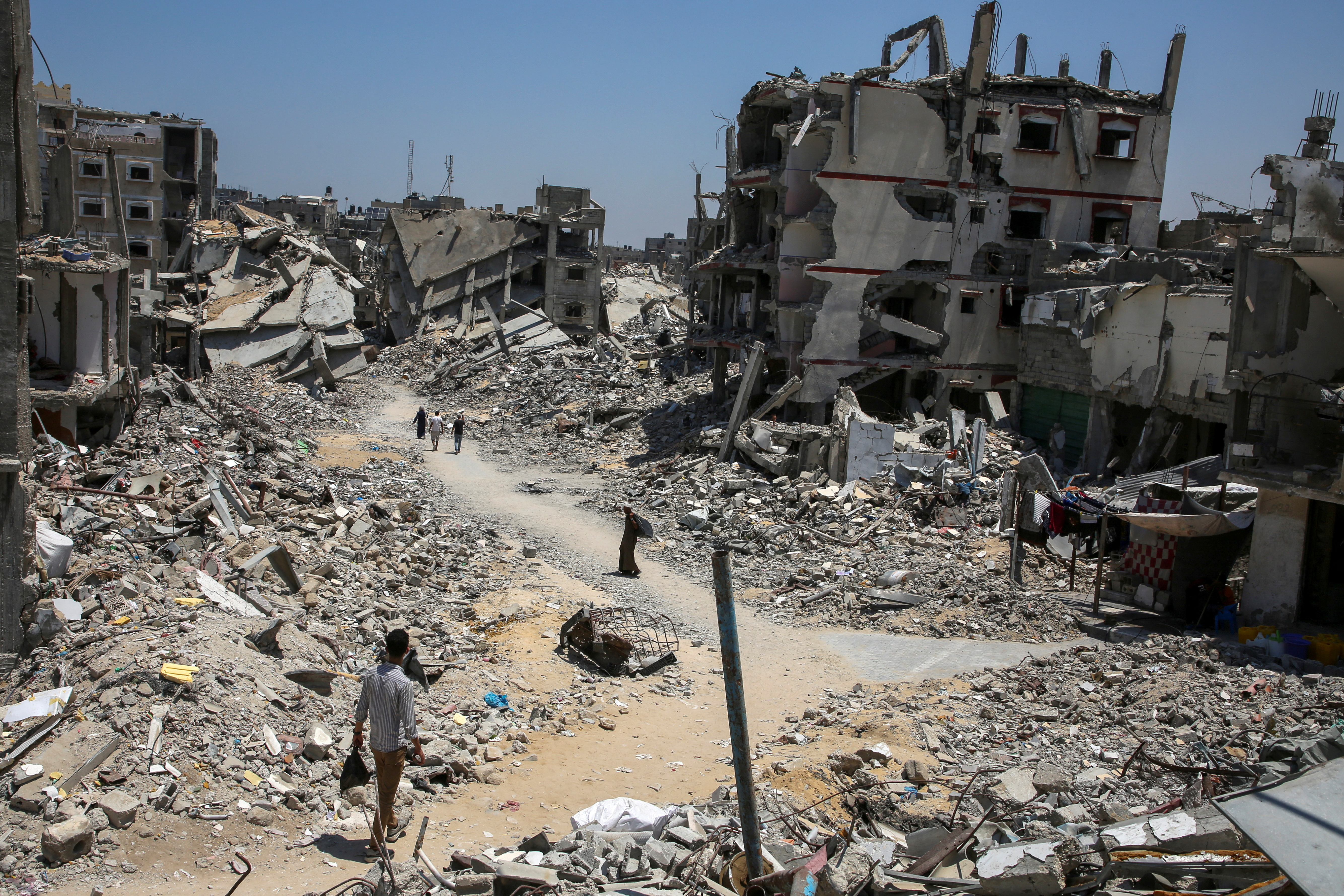 Palestinians walk past the rubble of houses destroyed during the Israeli military offensive, amid Israel-Hamas conflict, in Khan Younis in the southern Gaza Strip July 10, 2024. REUTERS/Hatem Khaled