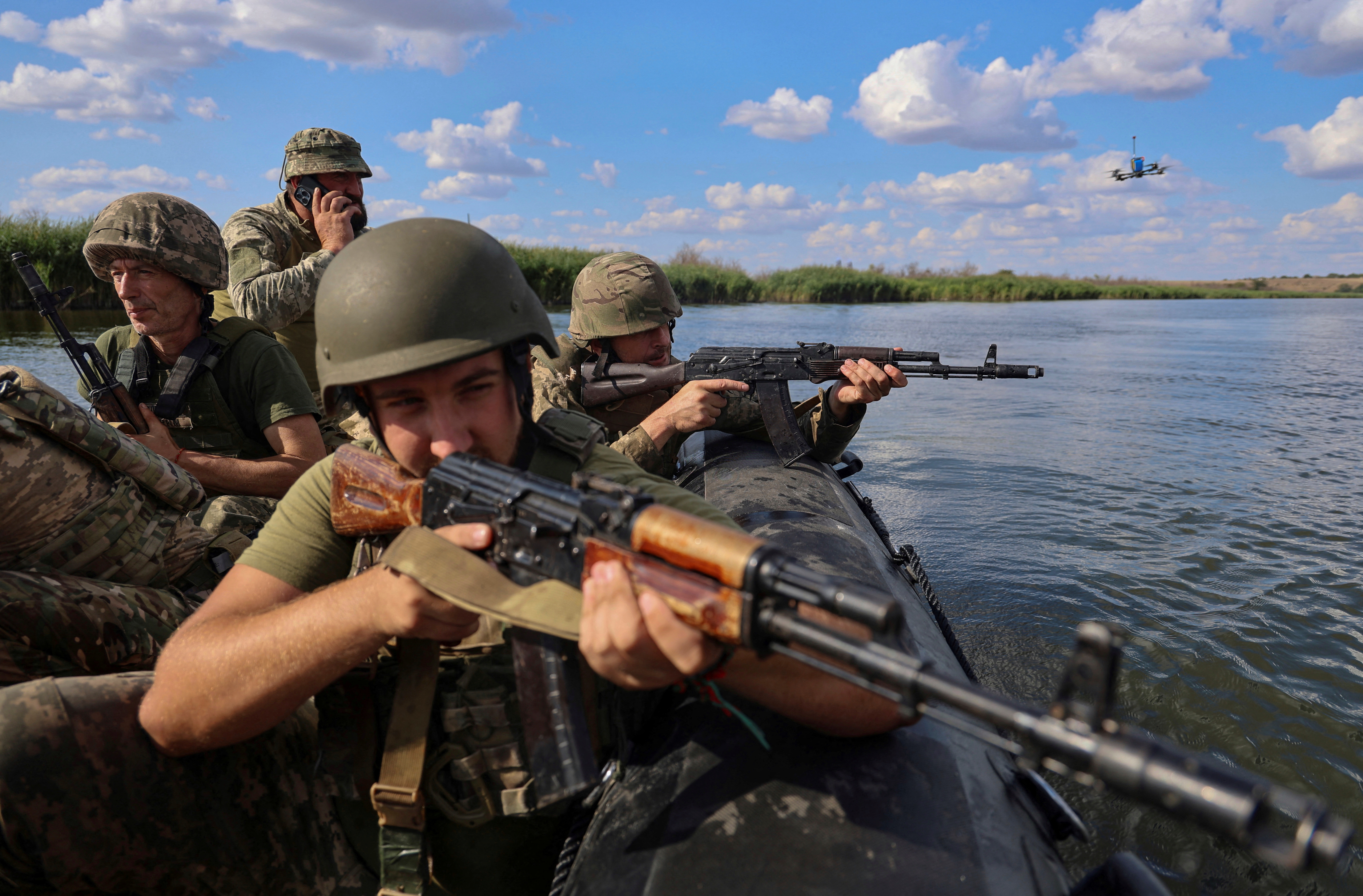Soldiers in a boat during a training exercise on the Kherson river. They are pointing their weapons.