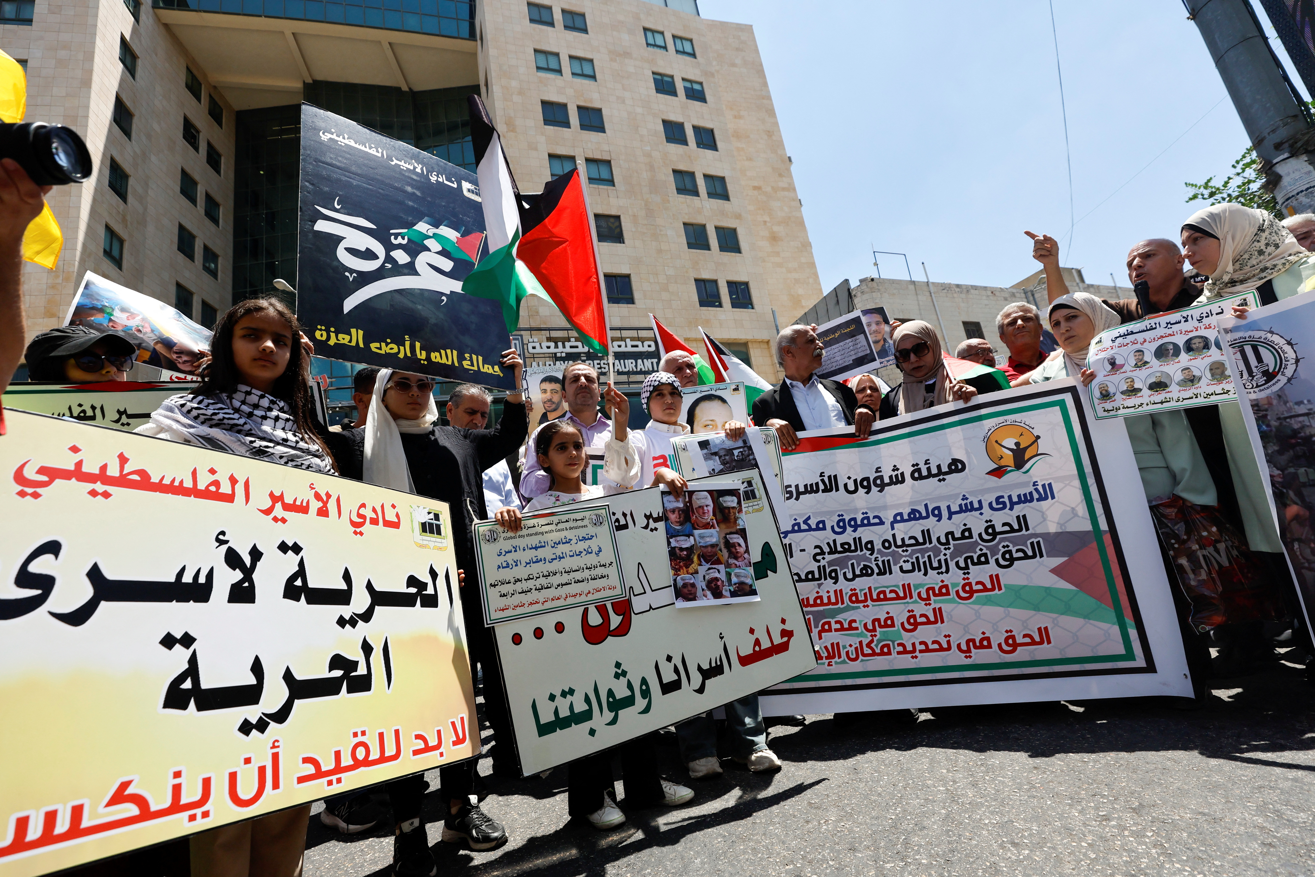 Palestinians hold placards during a protest in solidarity with Gaza and Palestinian prisoners in the Israeli jails, in Hebron in the Israeli-occupied West Bank August 3, 2024. REUTERS/Mussa Qawasma