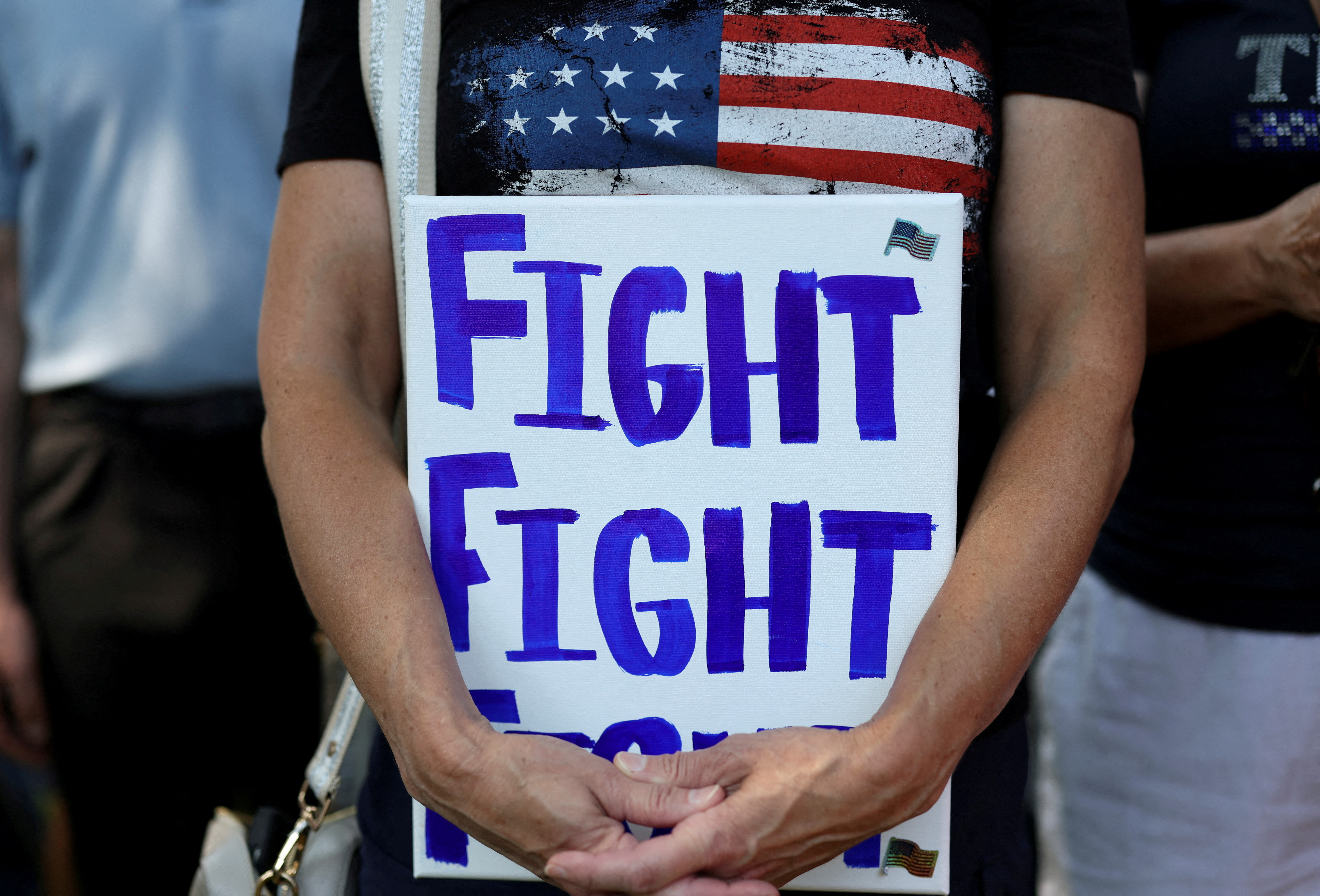 A Trump supporter holds a sign reading 'Fight fight fight'