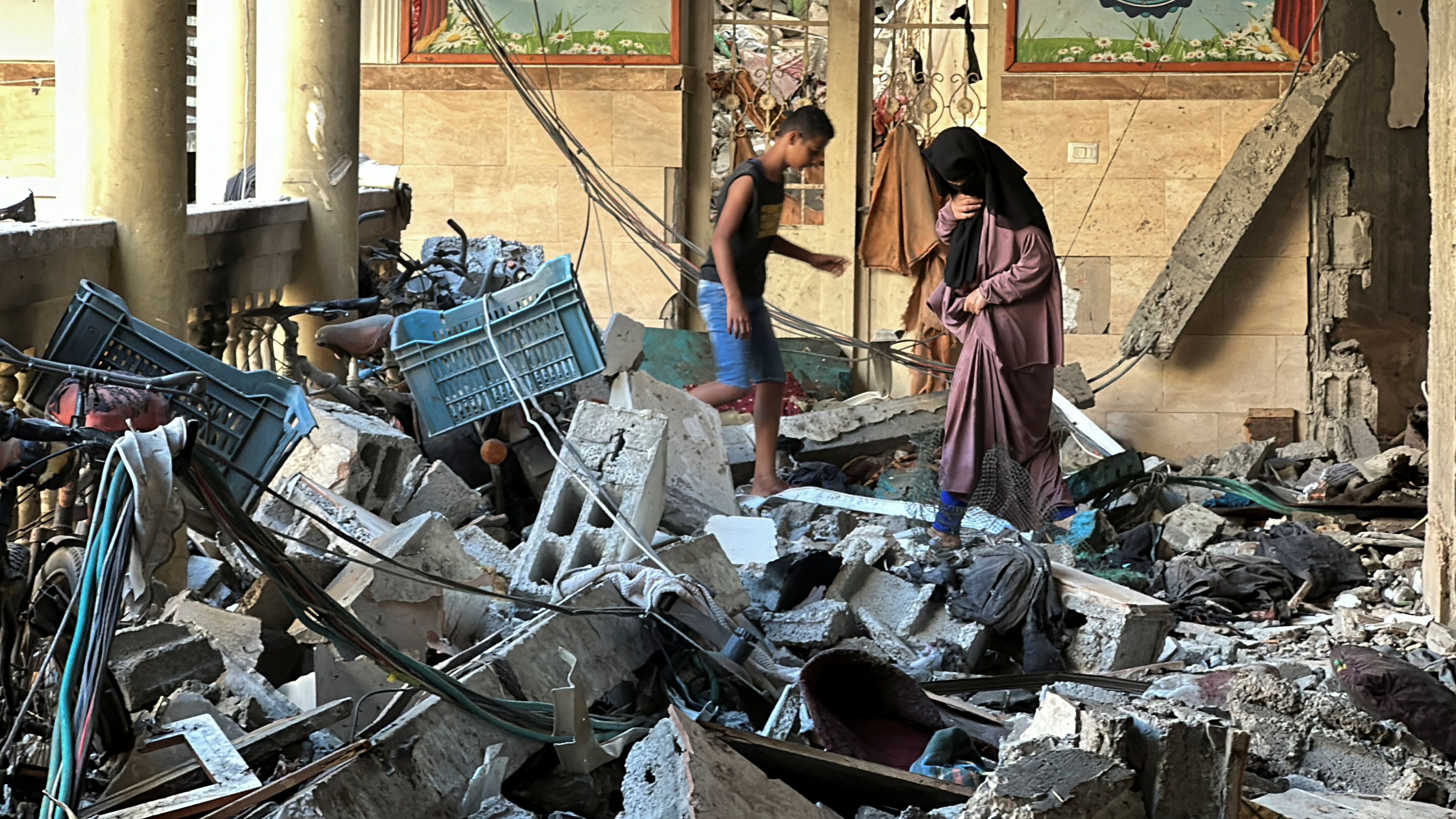 Palestinians inspect the site of an Israeli strike on a school sheltering displaced people,