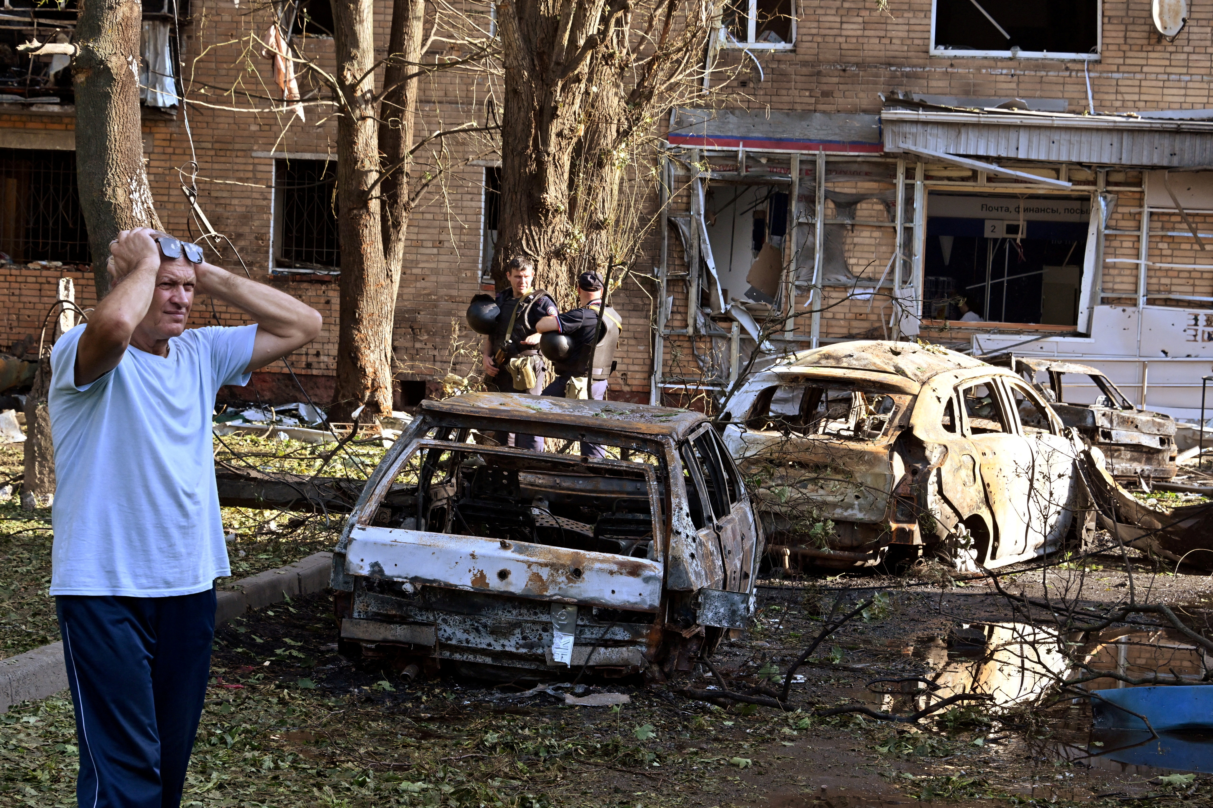 A man reacts while standing next to burnt-out remains of cars in the courtyard of a multi-storey residential building, which according to local authorities was hit by debris from a destroyed Ukrainian missile, in the course of Russia-Ukraine conflict in Kursk, Russia August 11, 2024. Kommersant Photo/Anatoliy Zhdanov via REUTERS RUSSIA OUT. NO COMMERCIAL OR EDITORIAL SALES IN RUSSIA. TPX IMAGES OF THE DAY