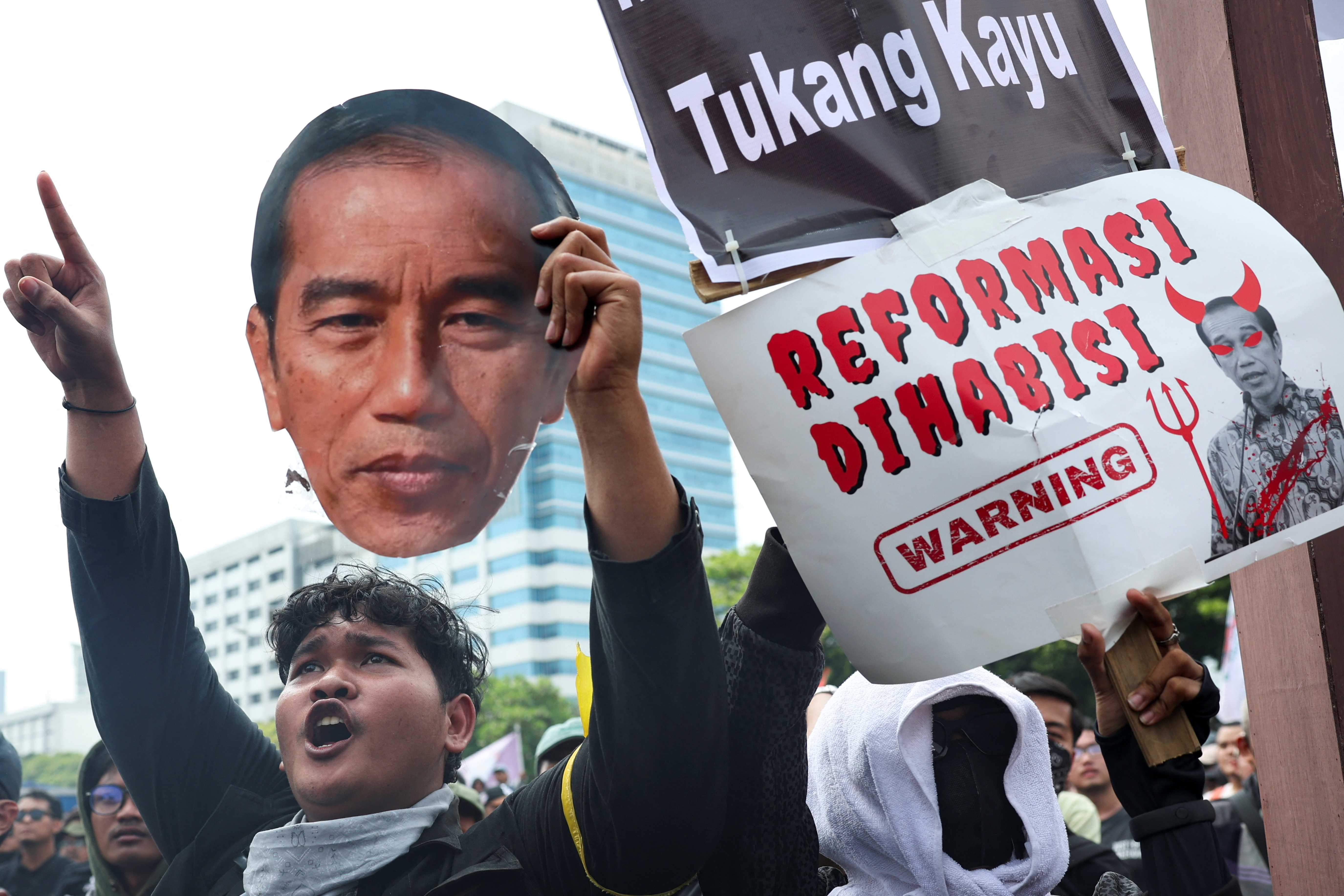People attend a protest outside the Indonesian Parliament against the revisions to the country's election law
