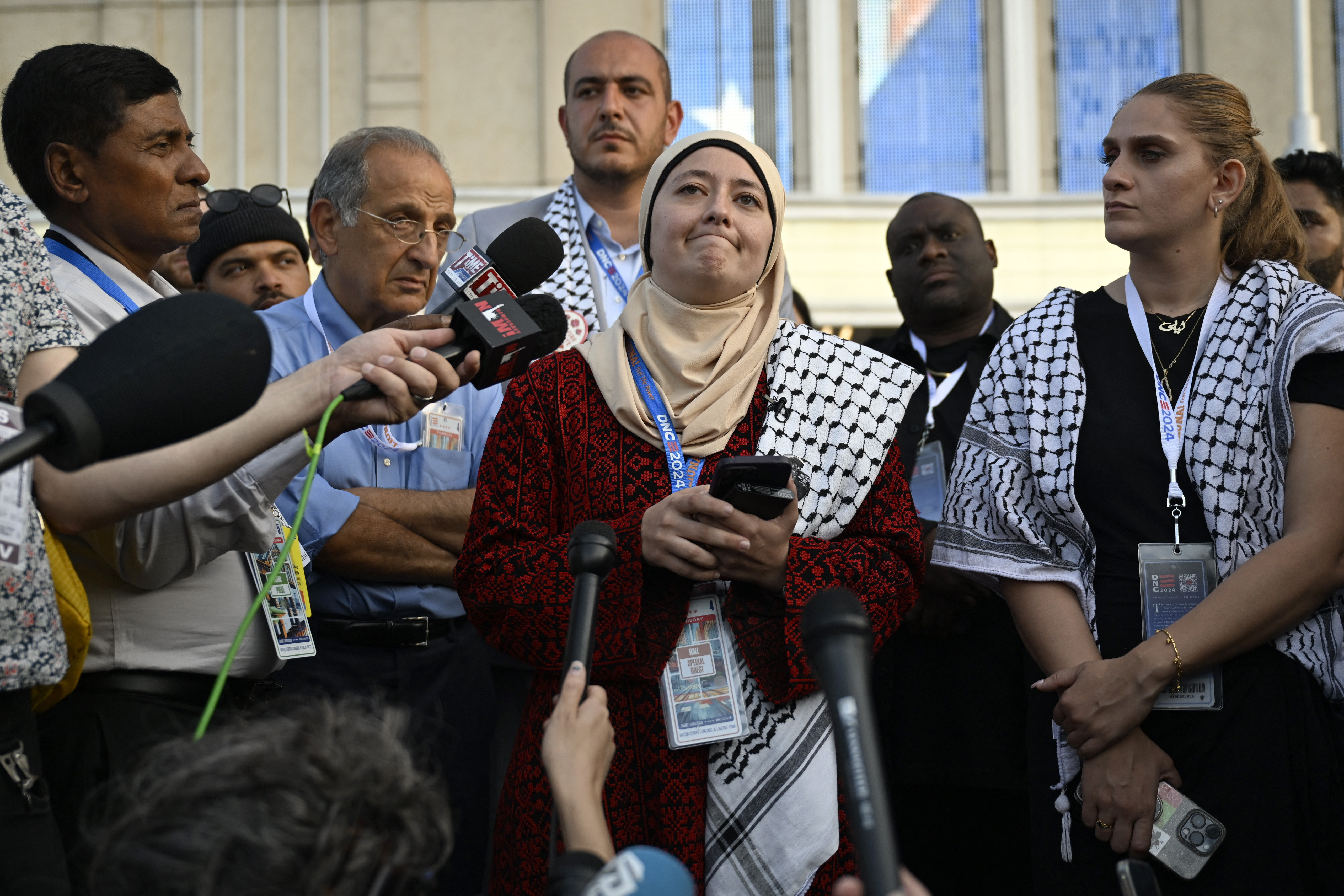 Ruwa Romman, with a keffiyeh draped over one shoulder, speaks at a press conference outside the Democratic National Convention.
