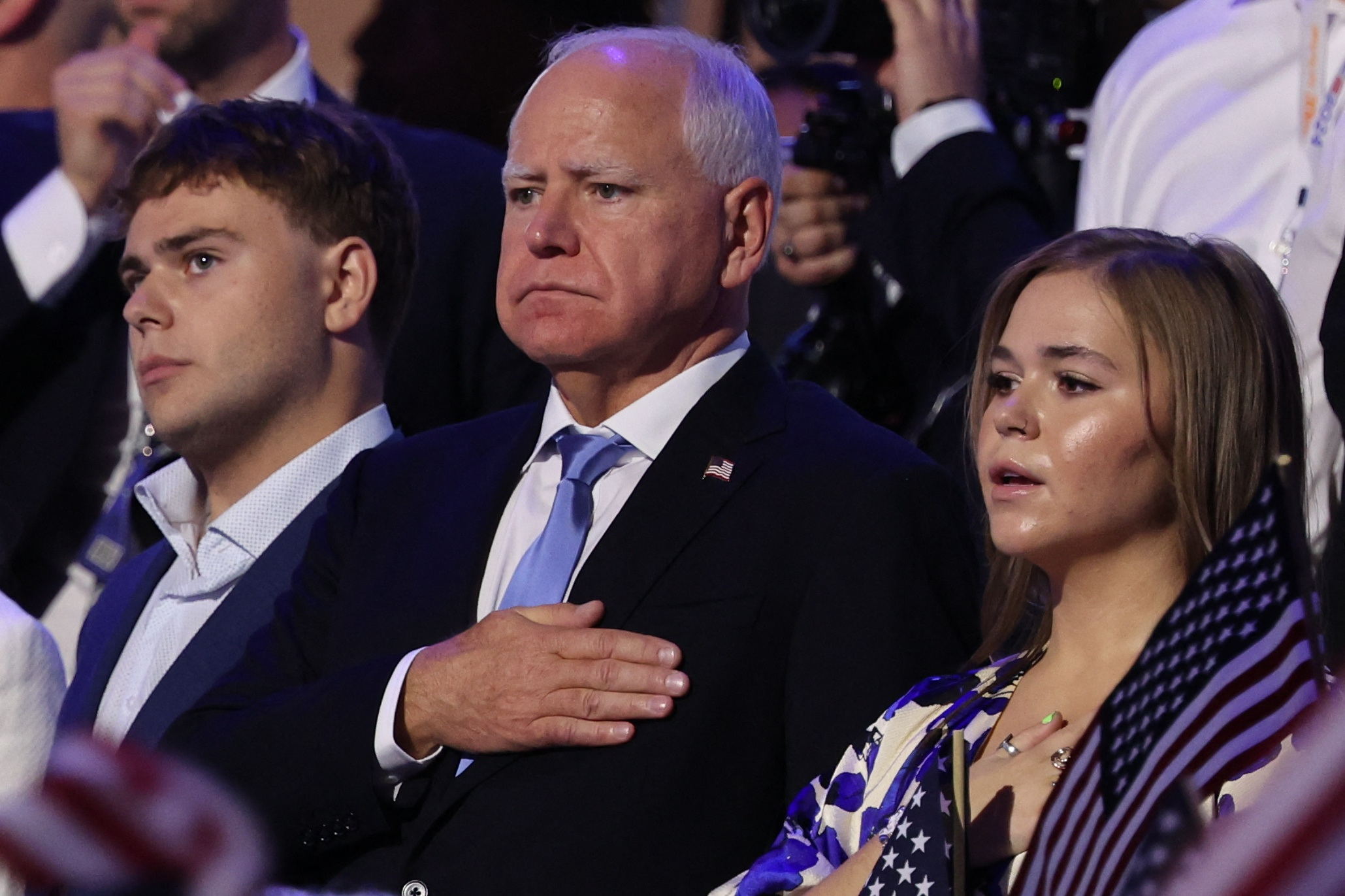 Tim Walz stands with his hand over his heart for the pledge of allegiance, alongside his kids Hope and Gus.