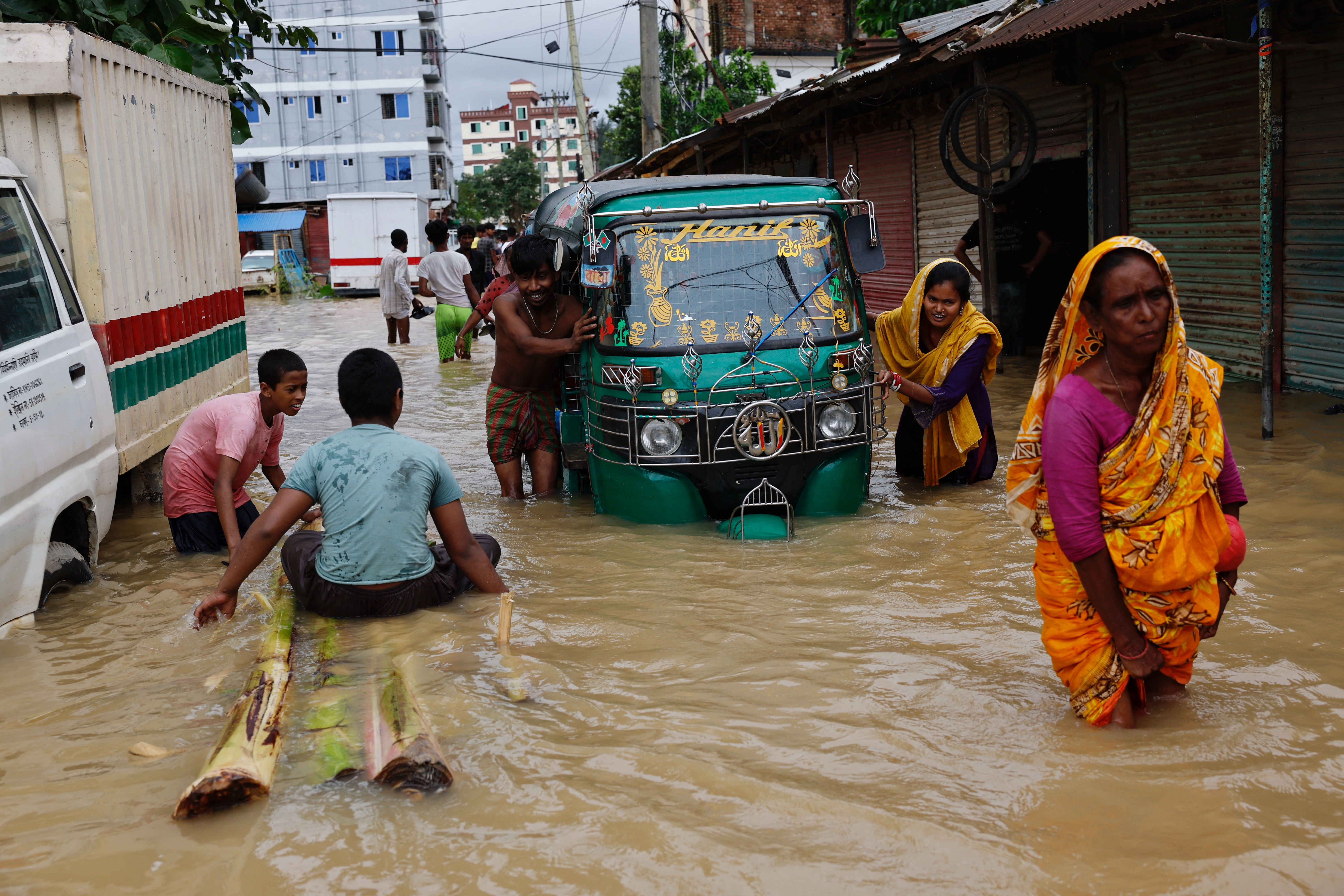 People move an auto-rickshaw through flood water after a severe flood hits the Lalpol