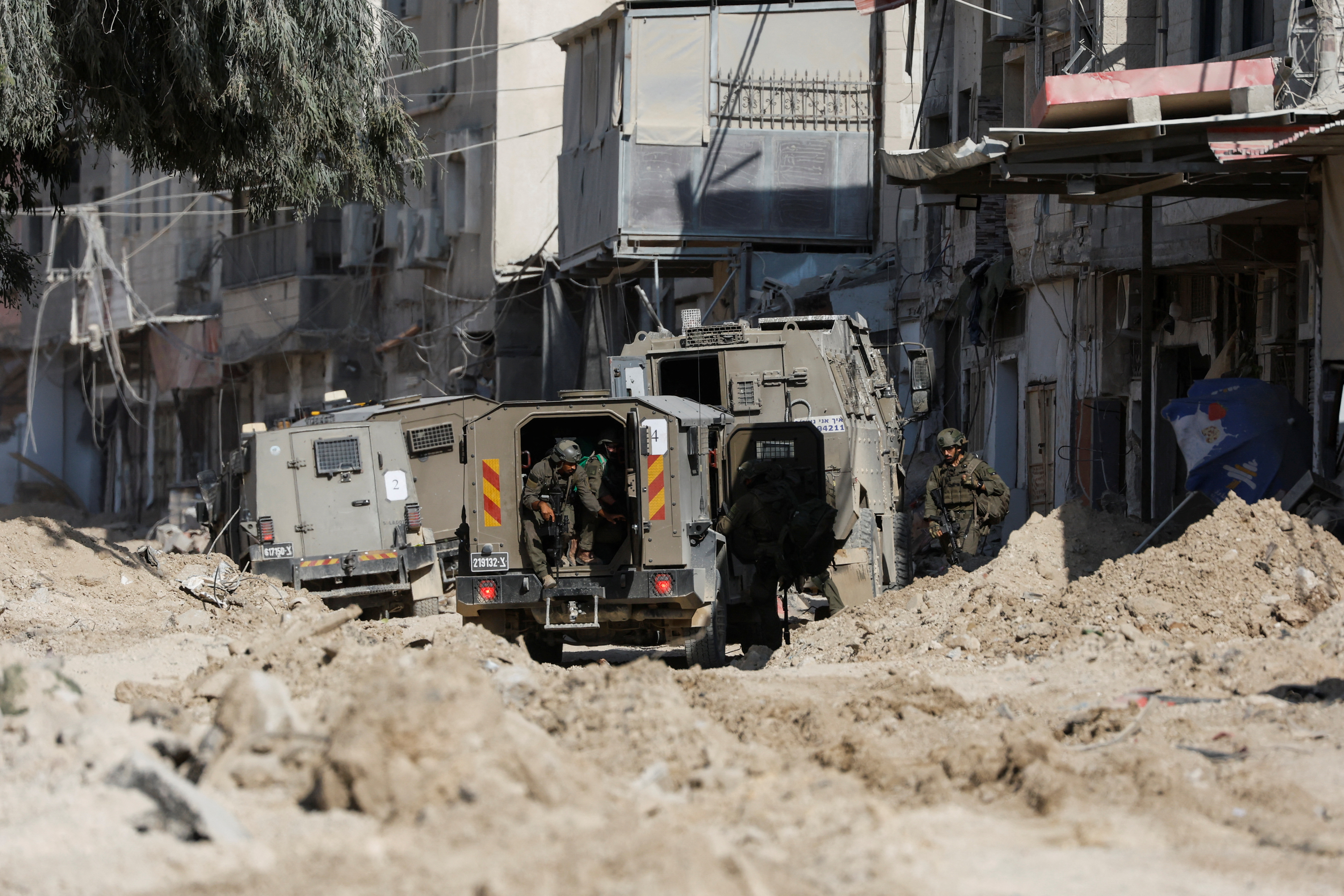 Israeli soldiers stand near a military vehicle during an Israeli raid in Nour Shams camp in Tulkarm, in the Israeli-occupied West Bank