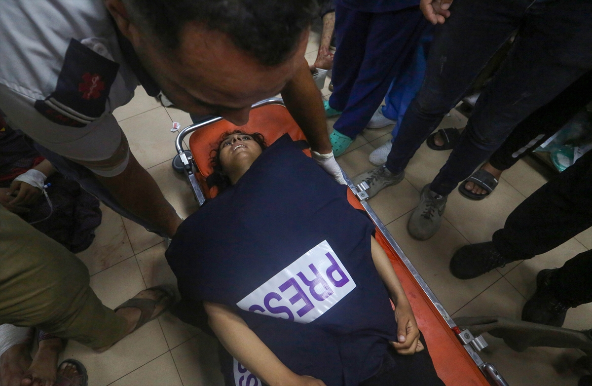 a woman in a press vest is seen on a stretcher in a hospital