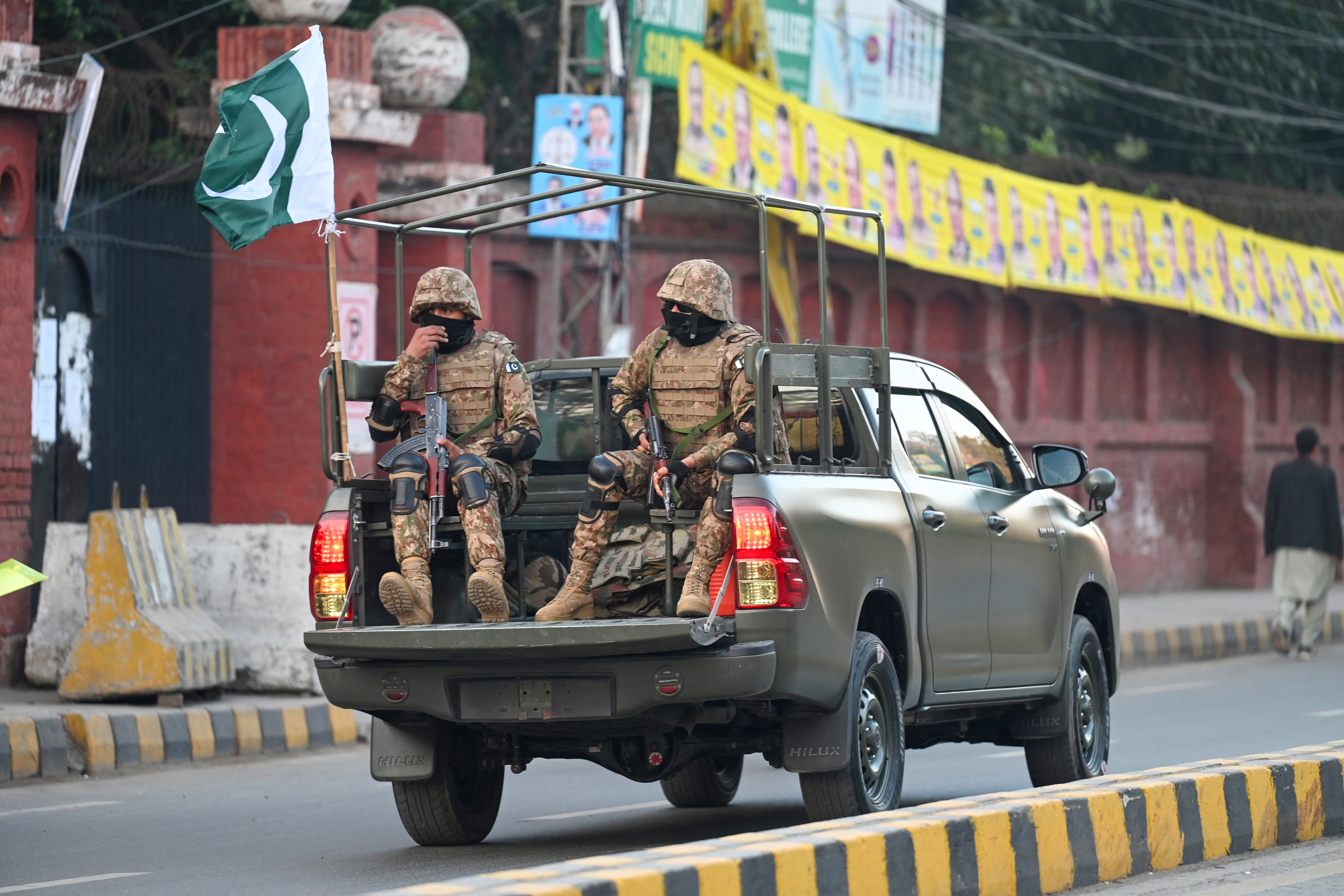 Military troops patrol near a polling station during Pakistan's national elections in Lahore on February 8, 2024. Millions of Pakistanis voted on February 8 in an election marred by rigging allegations, with authorities suspending mobile phone services throughout the day and the country's most popular politician in jail. (Photo by Aamir QURESHI / AFP)
