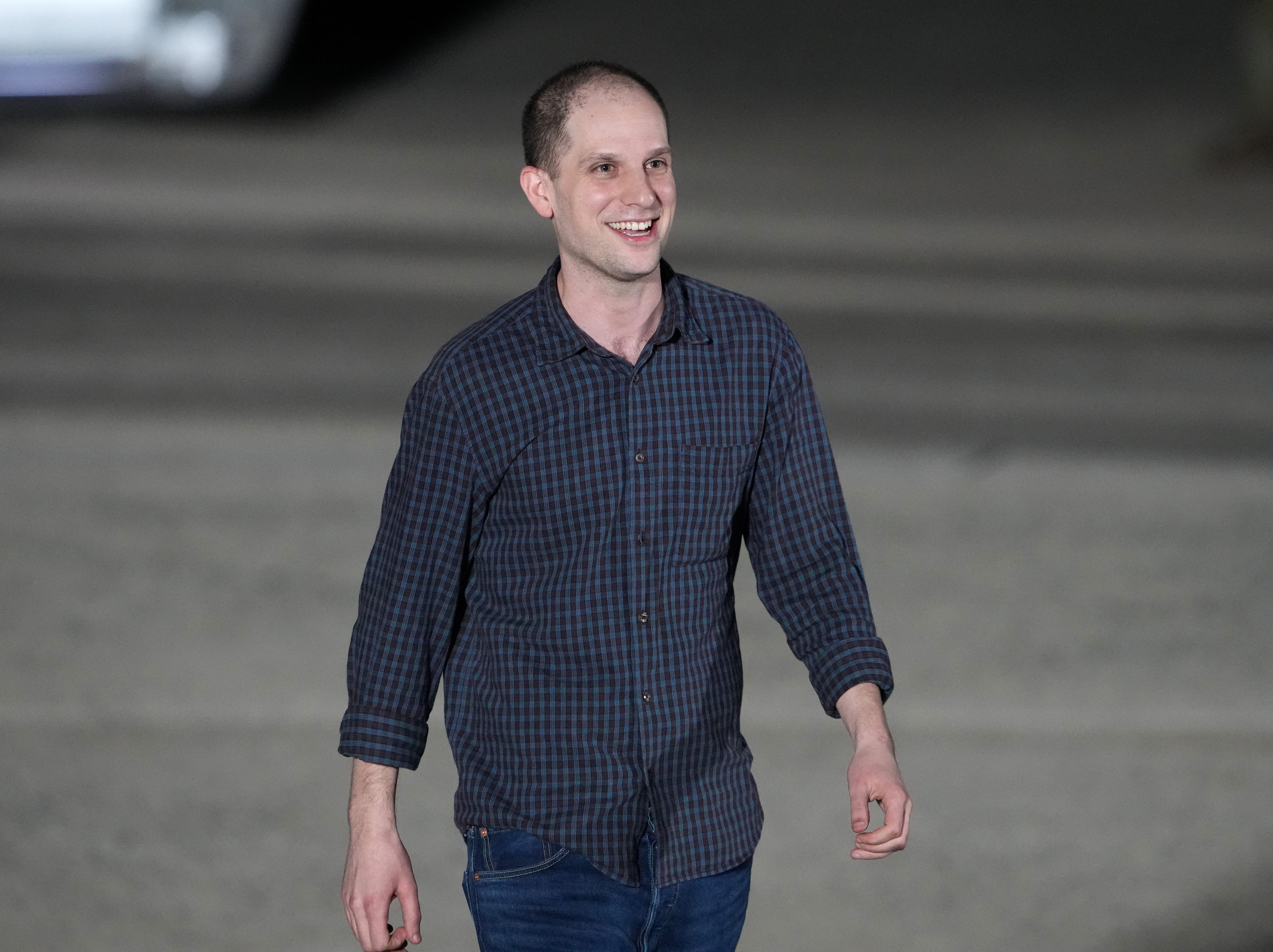 Evan Gershkovich walking on the tarmac at the airport. He looks thin, but very happy.