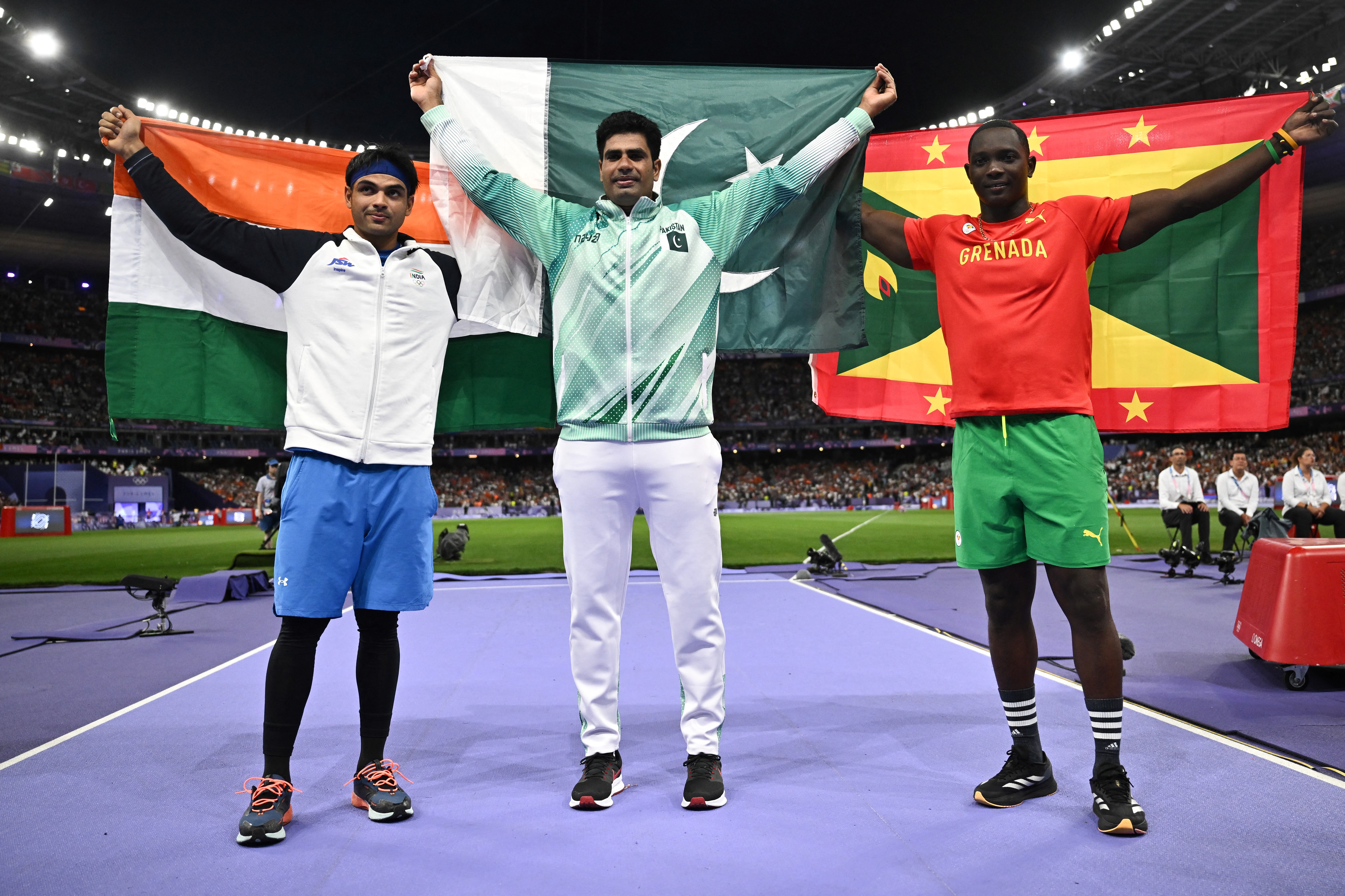 (From L) Silver medallist India's Neeraj Chopra, Gold medallist Pakistan's Arshad Nadeem and Bronze medallist Grenada's Anderson Peters celebrate after competing in the men's javelin throw final of the athletics event at the Paris 2024 Olympic Games at Stade de France in Saint-Denis, north of Paris, on August 8, 2024. (Photo by Ben STANSALL / AFP)