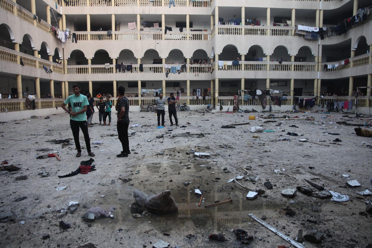 People gather in the yard of a school used by displaced Palestinians as a temporary shelter, after it was hit by an Israeli strike in Gaza City on August 10, 2024, that killed more than 90 people amid the ongoing conflict between Israel and Hamas militants. (Photo by Omar AL-QATTAA / AFP)