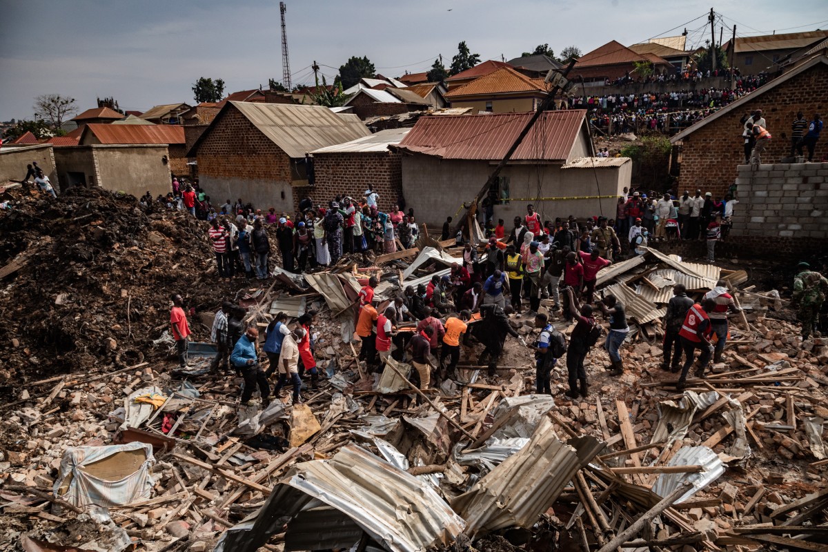Red Cross officers together with community members carry a recovered body from debris following a landfill collapse in Kampala on August 10, 2024. - Eight people including two children were killed when mountains of garbage collapsed at a landfill in the Ugandan capital Kampala on August 10, the city authority said. (Photo by BADRU KATUMBA / AFP)