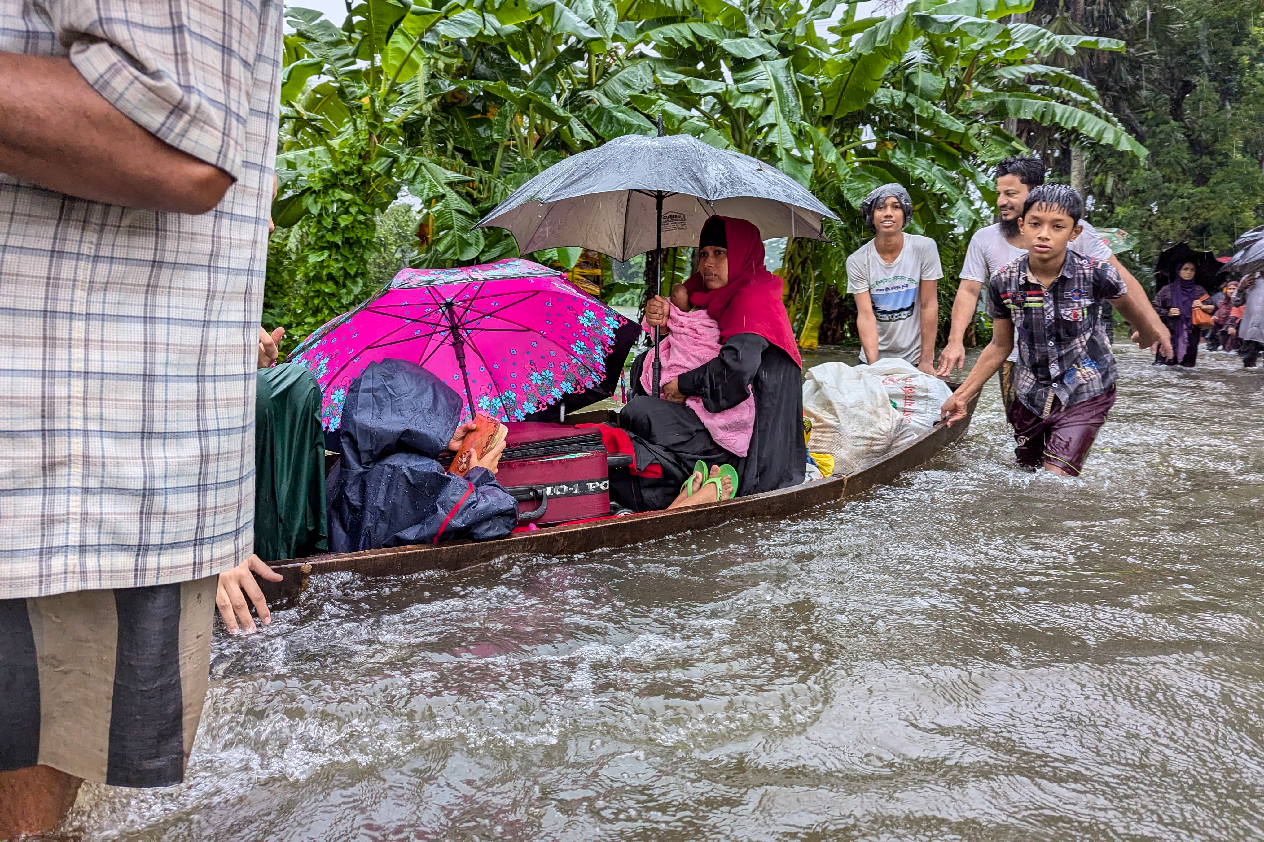 People wade through flood waters in Feni
