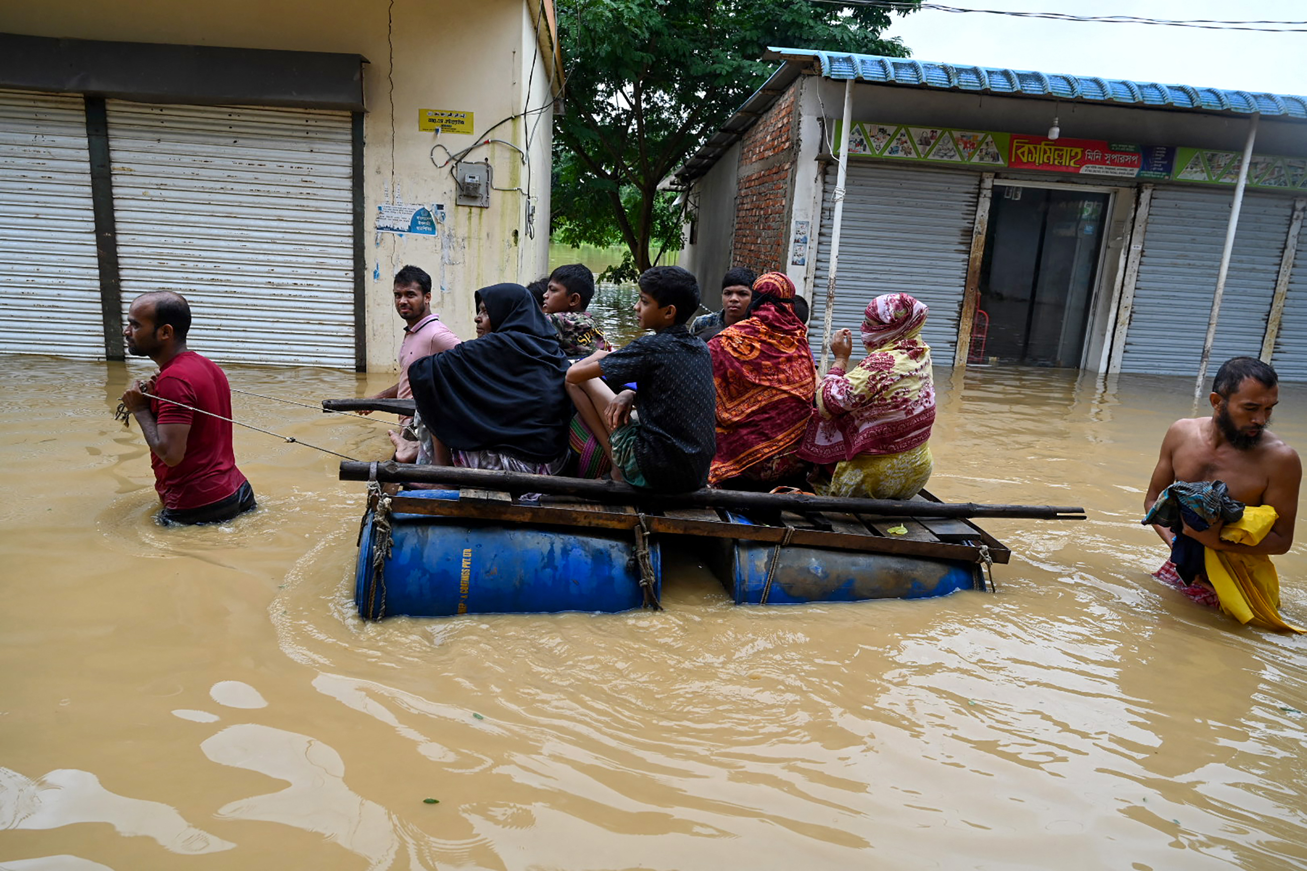 People wade through flood waters in Feni